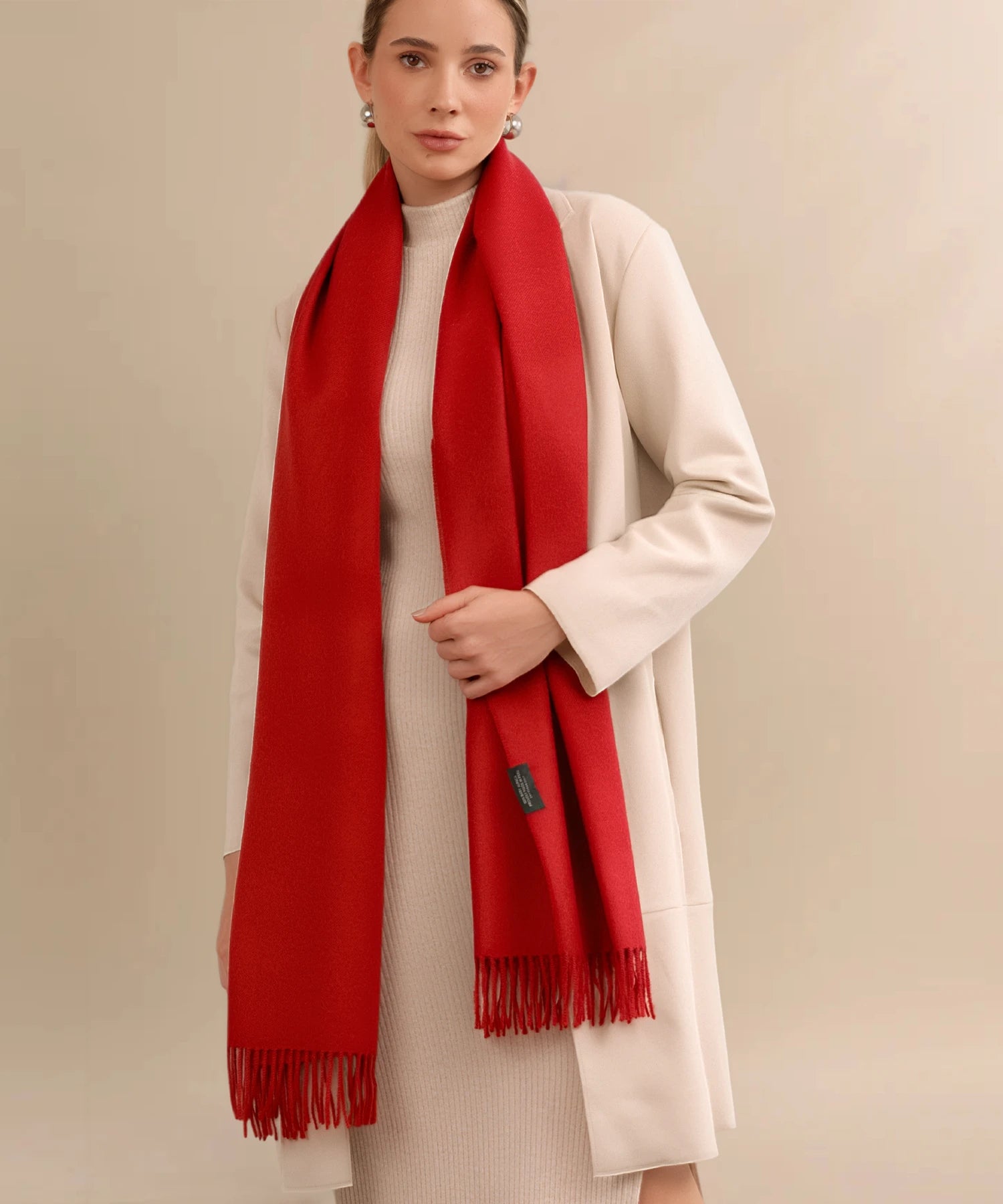 Woman wearing a red scarf and beige coat against a beige background