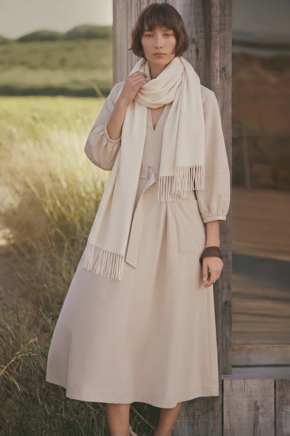 Woman wearing a beige dress and scarf standing in a field