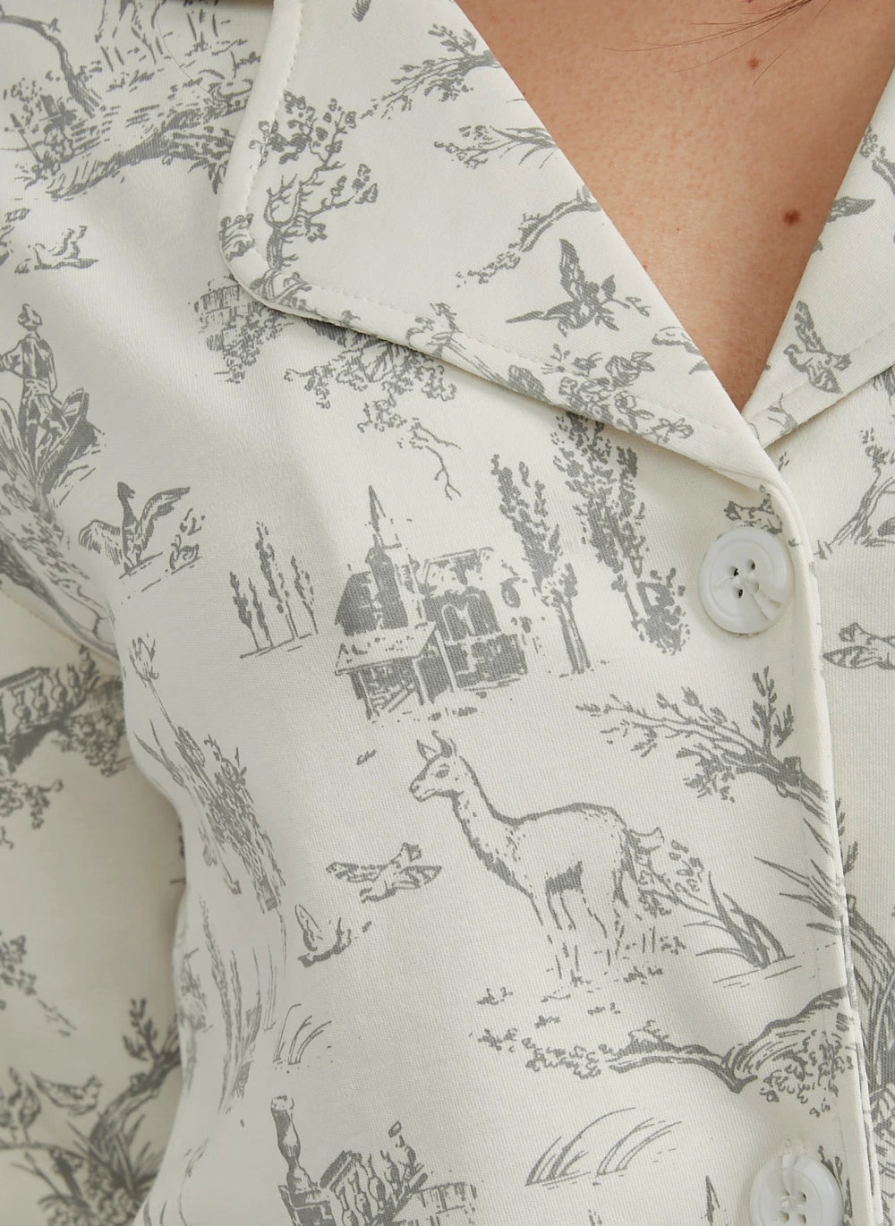 Close-up of a shirt with a nature-themed pattern featuring animals and buildings.