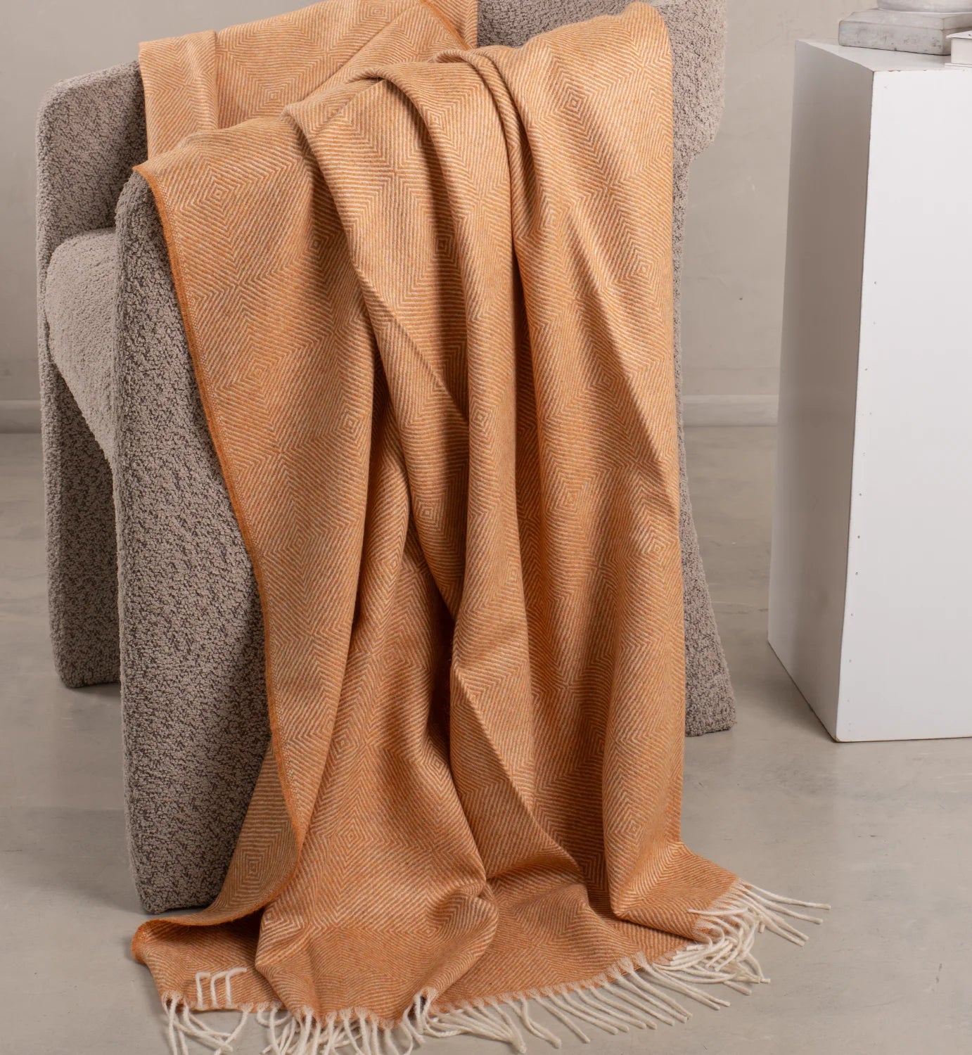Brown textured throw blanket draped over a gray armchair in a minimalistic room.