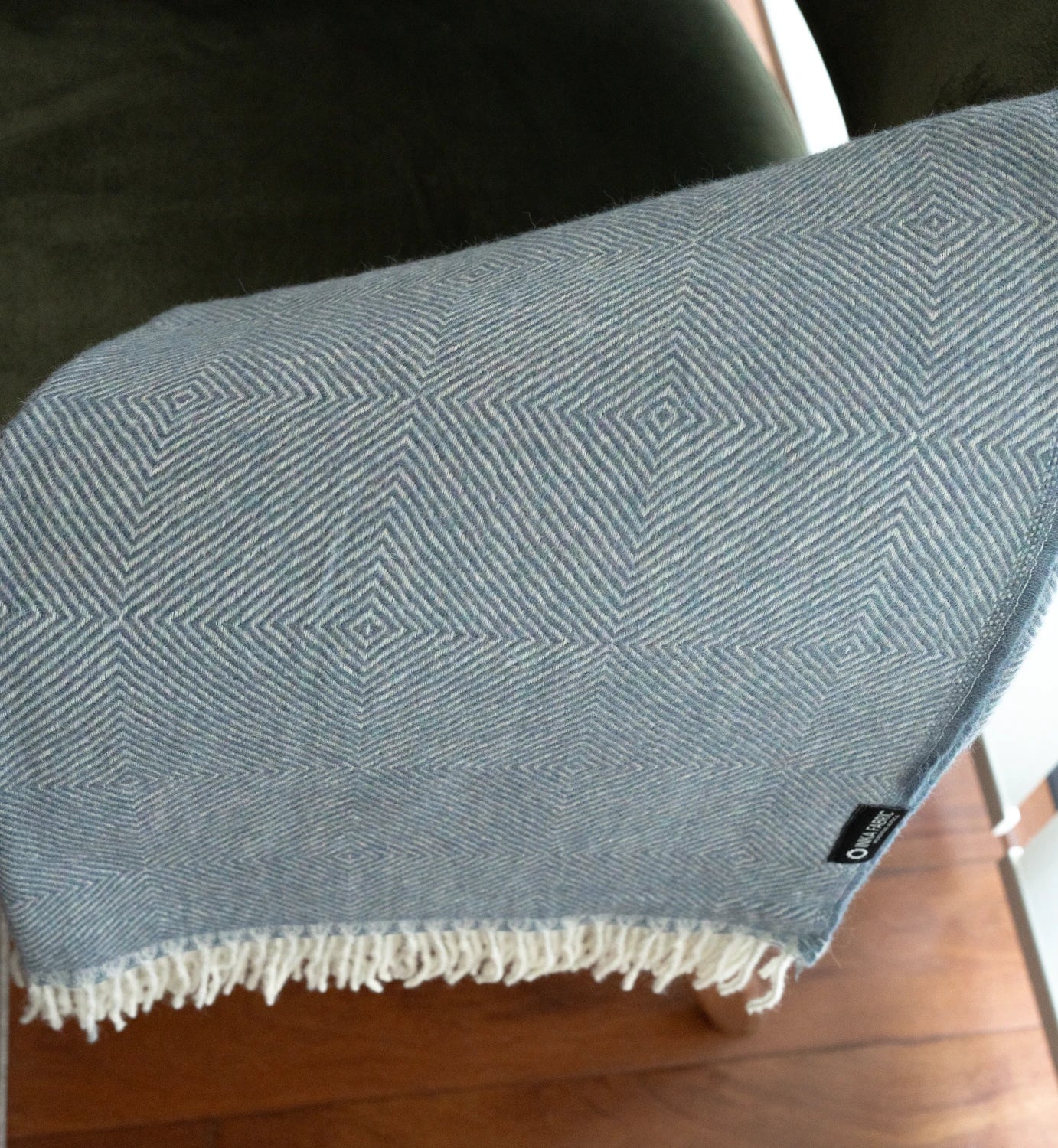 Blue patterned blanket with white fringe on a wooden surface