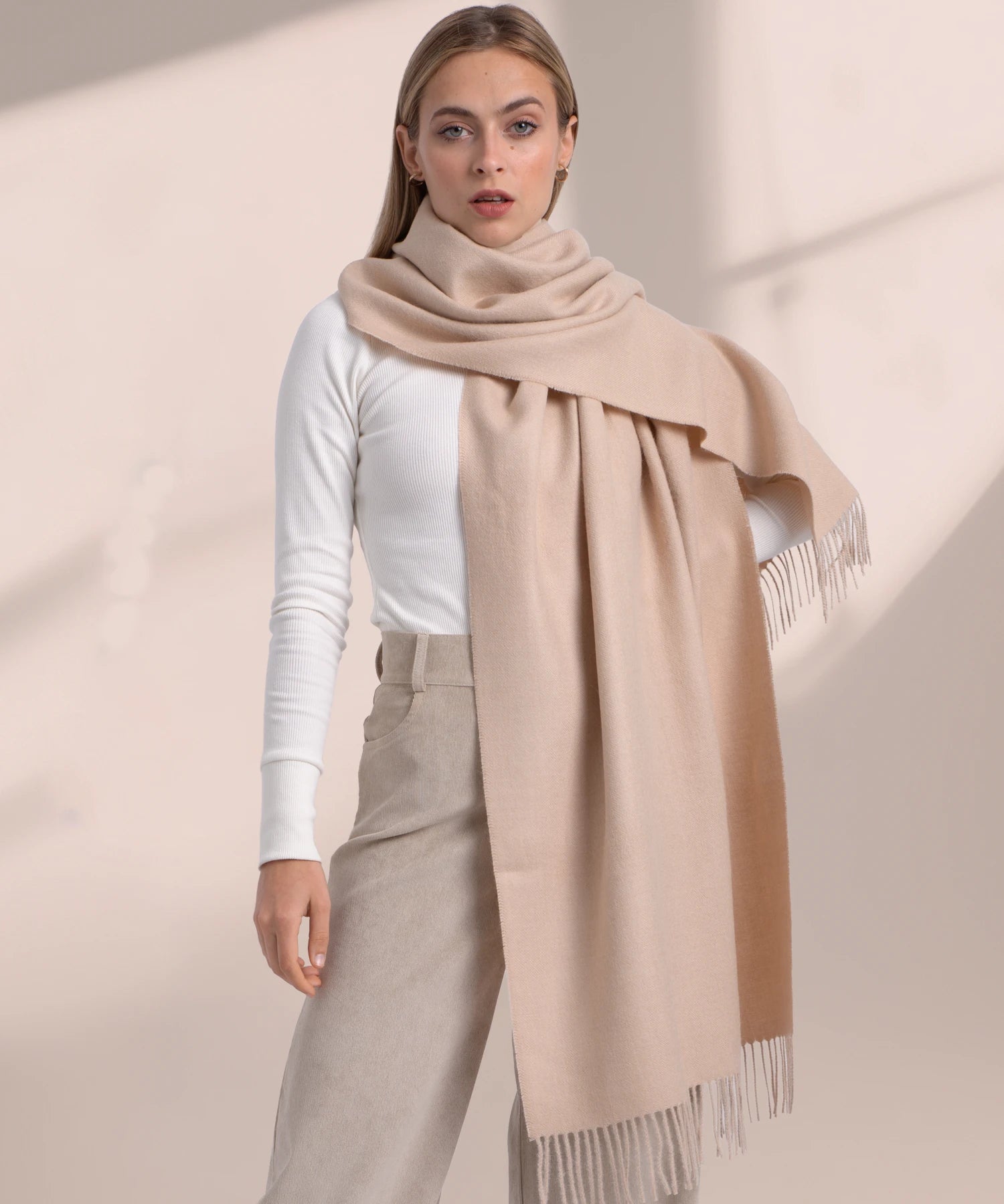 Woman wearing a beige scarf with a plain background
