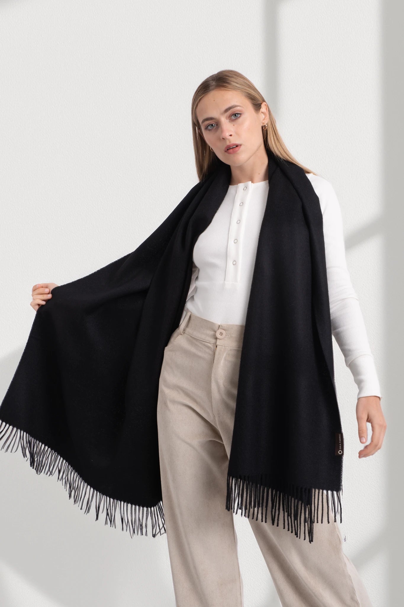 Woman wearing a black scarf with fringes on a white background