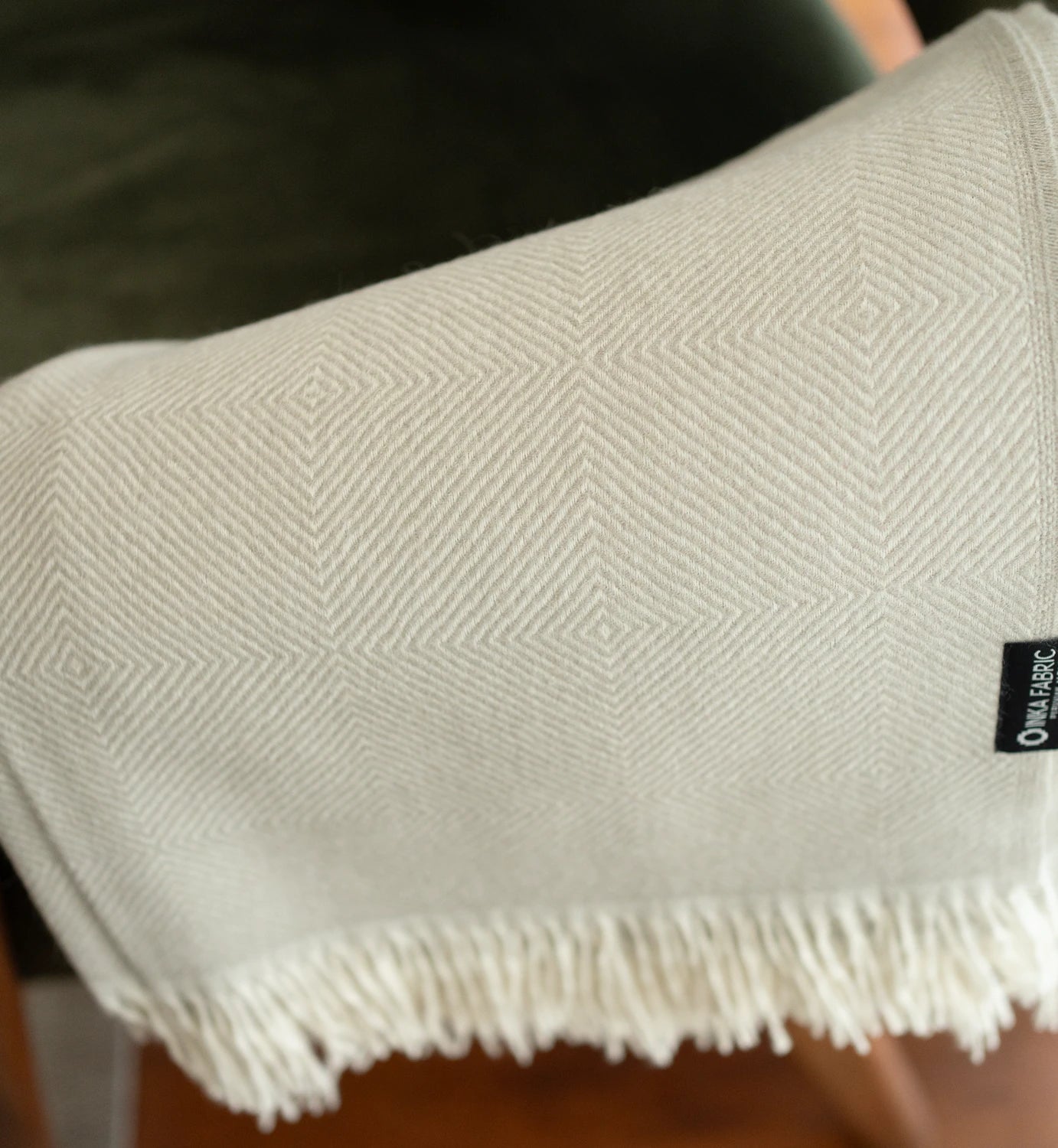 Textured fabric with a diamond pattern and frayed edge, featuring a brand label.