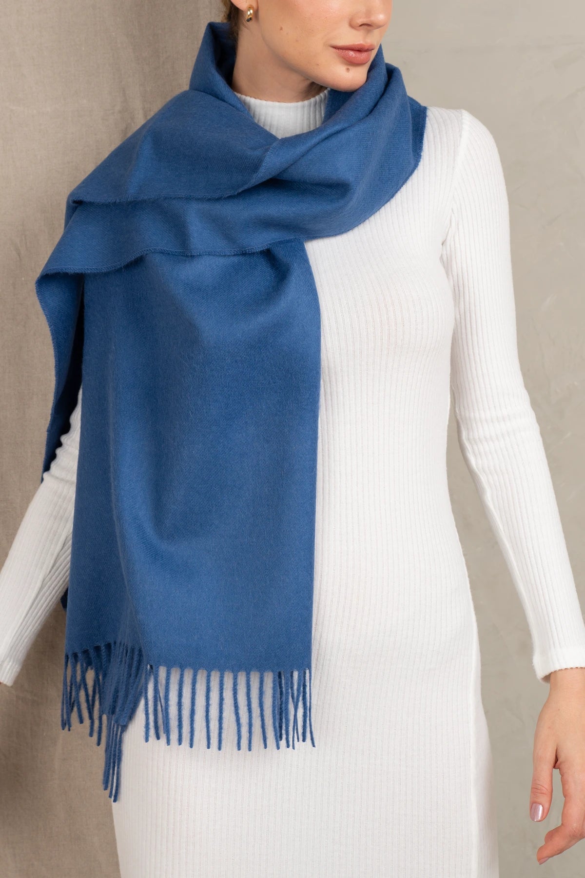 Person wearing a baby alpaca blue scarf with a white background