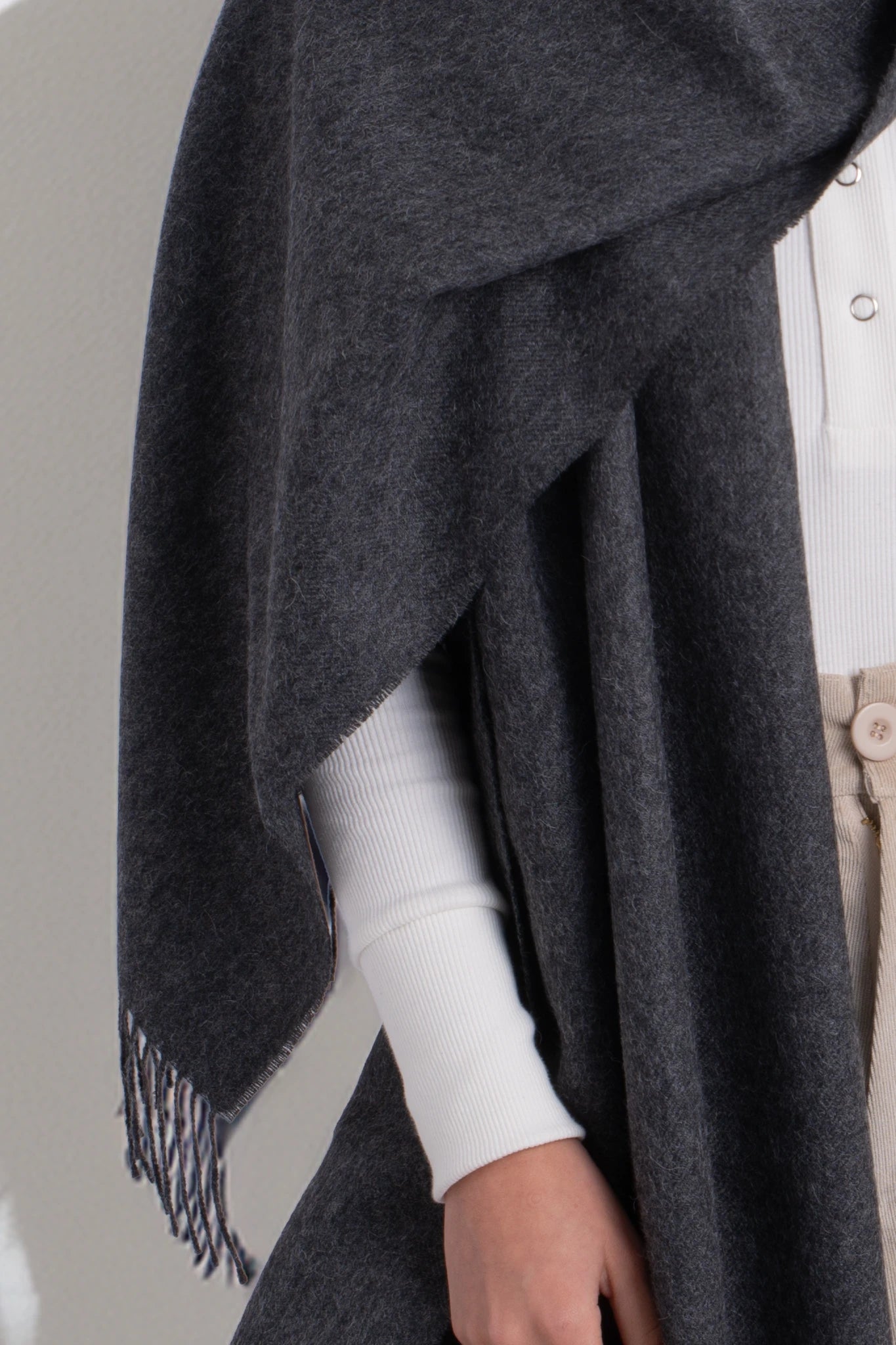 Dark gray poncho draped over a person with a neutral background