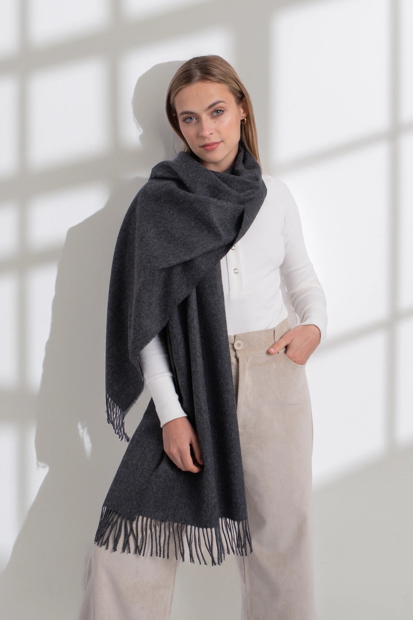 Woman wearing a dark gray scarf in a bright room