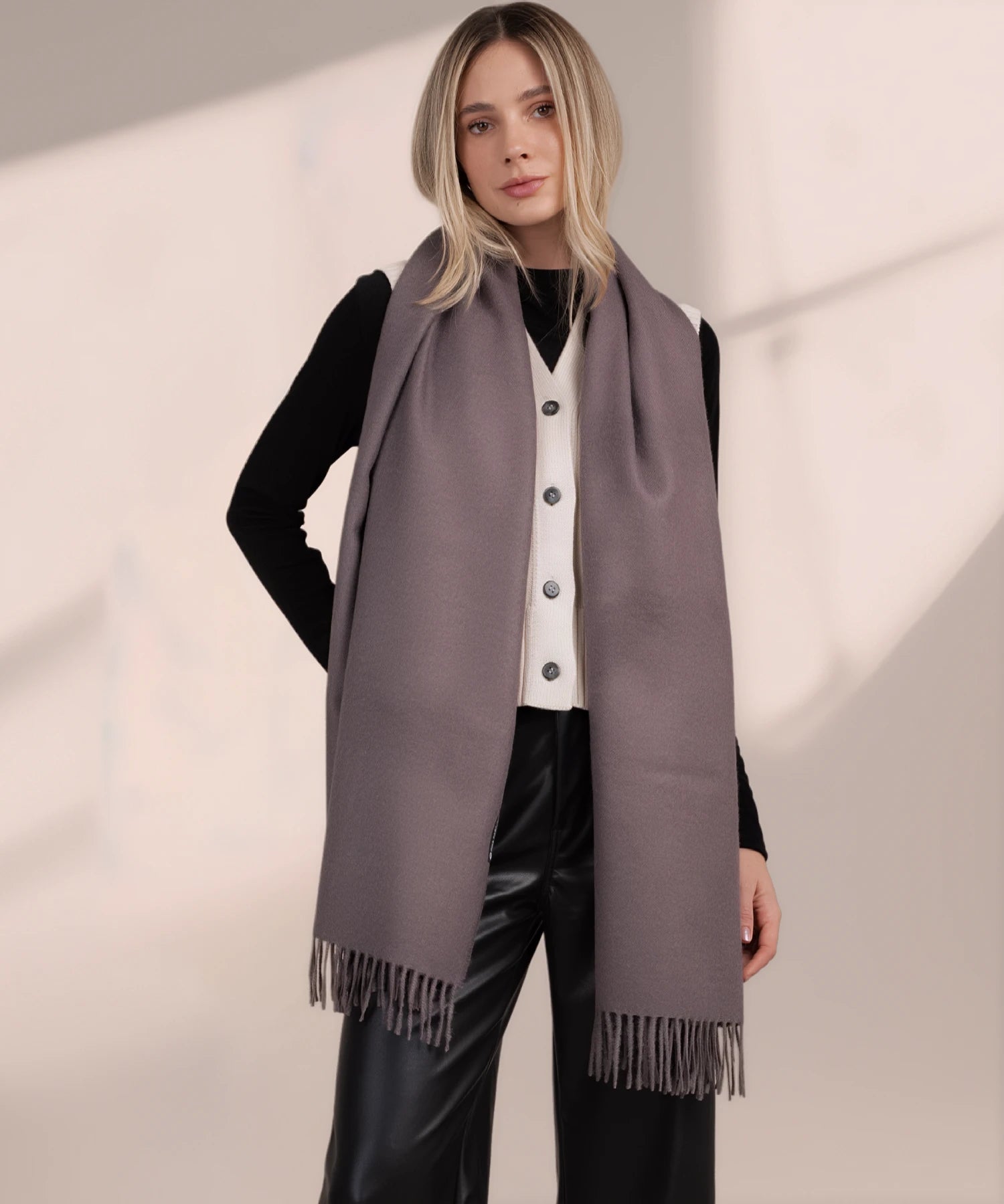 Woman wearing a gray scarf with a plain background