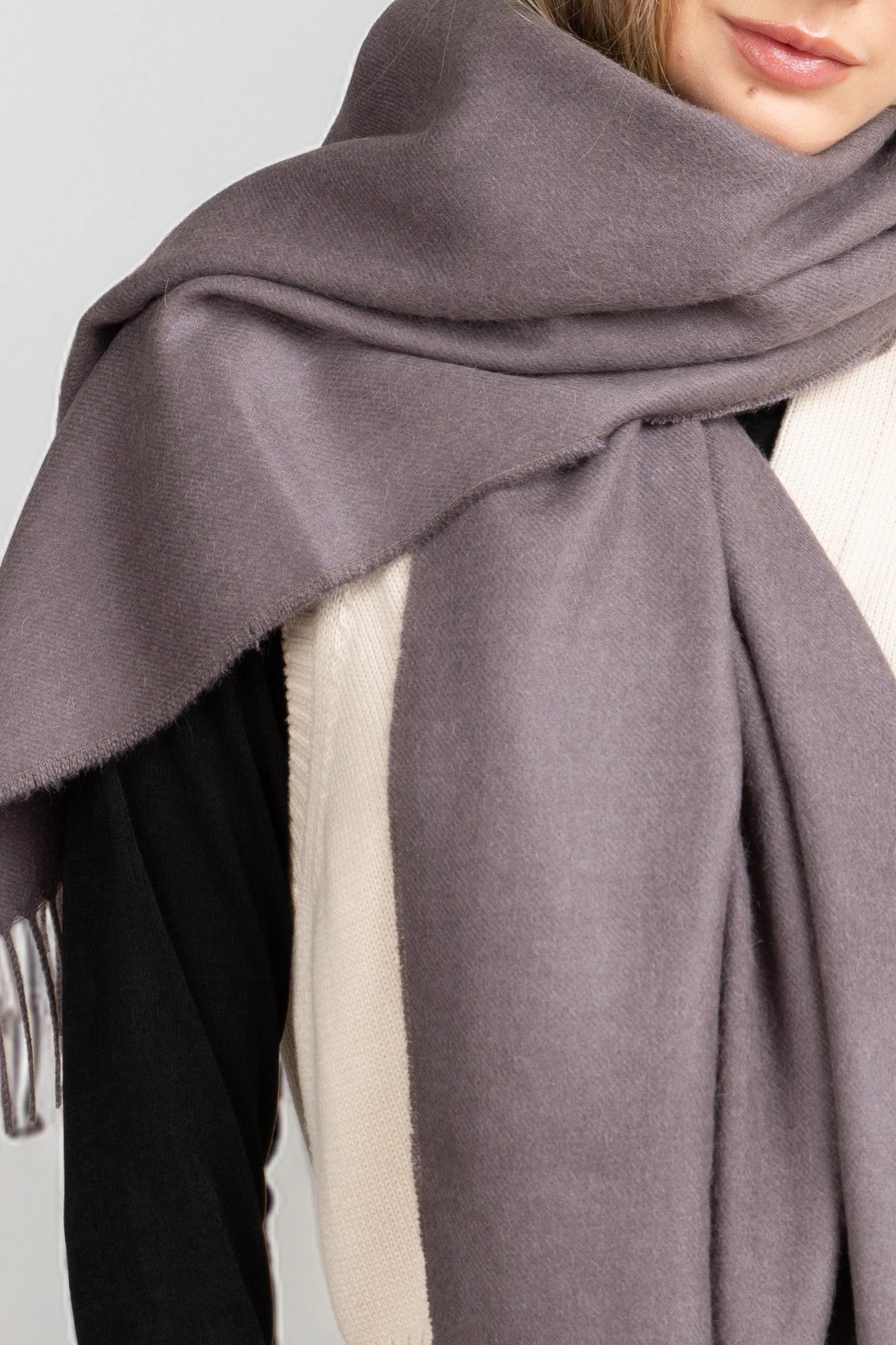 Close-up of a person wearing a gray scarf with a neutral background