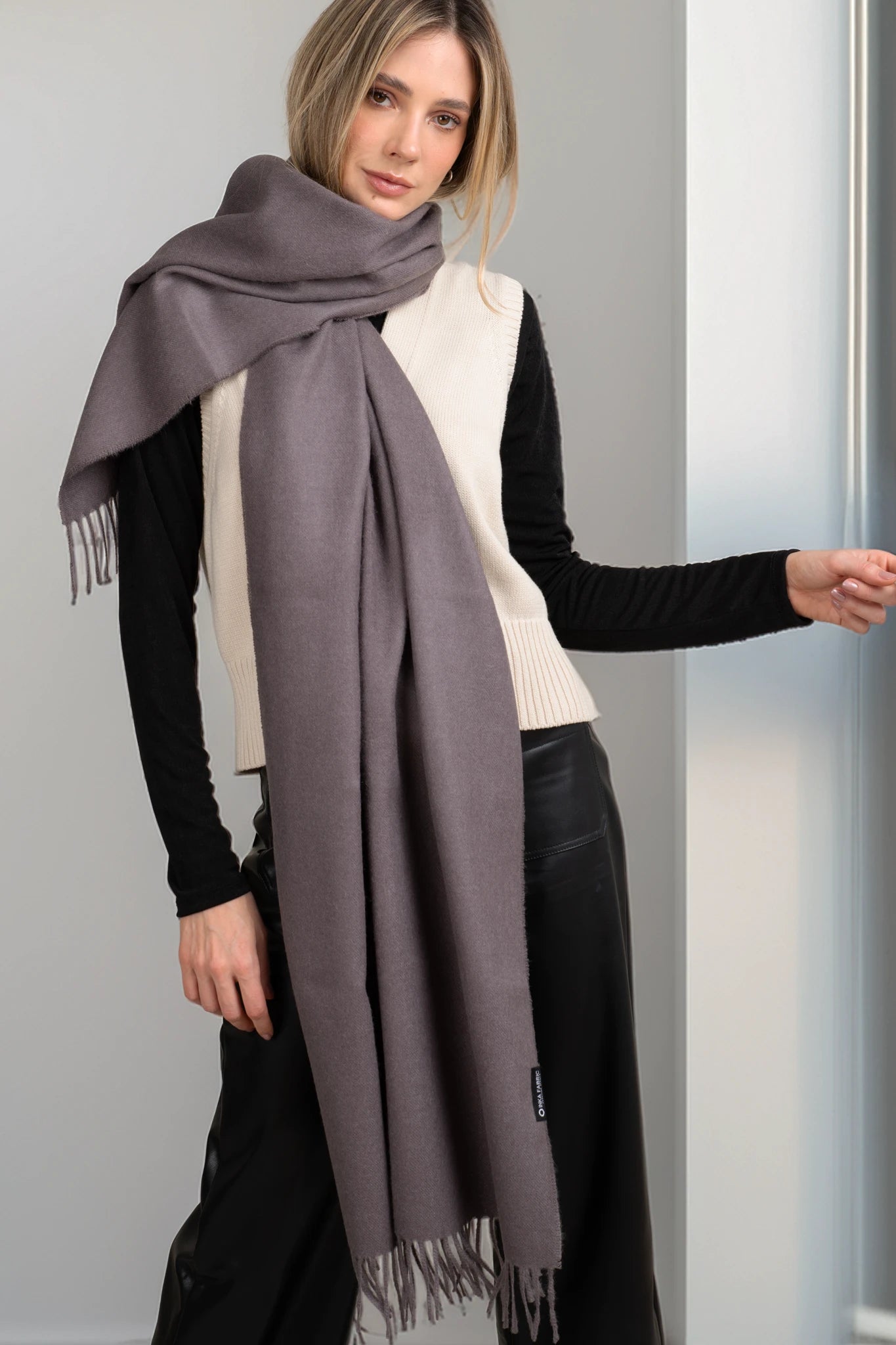 Woman wearing a gray scarf with a plain background