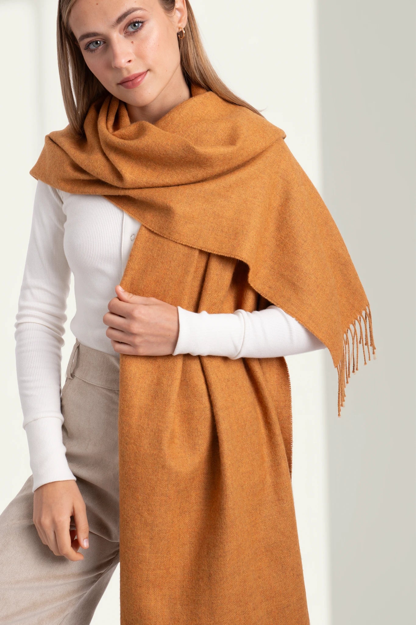 Woman wearing a large orange scarf with a white background