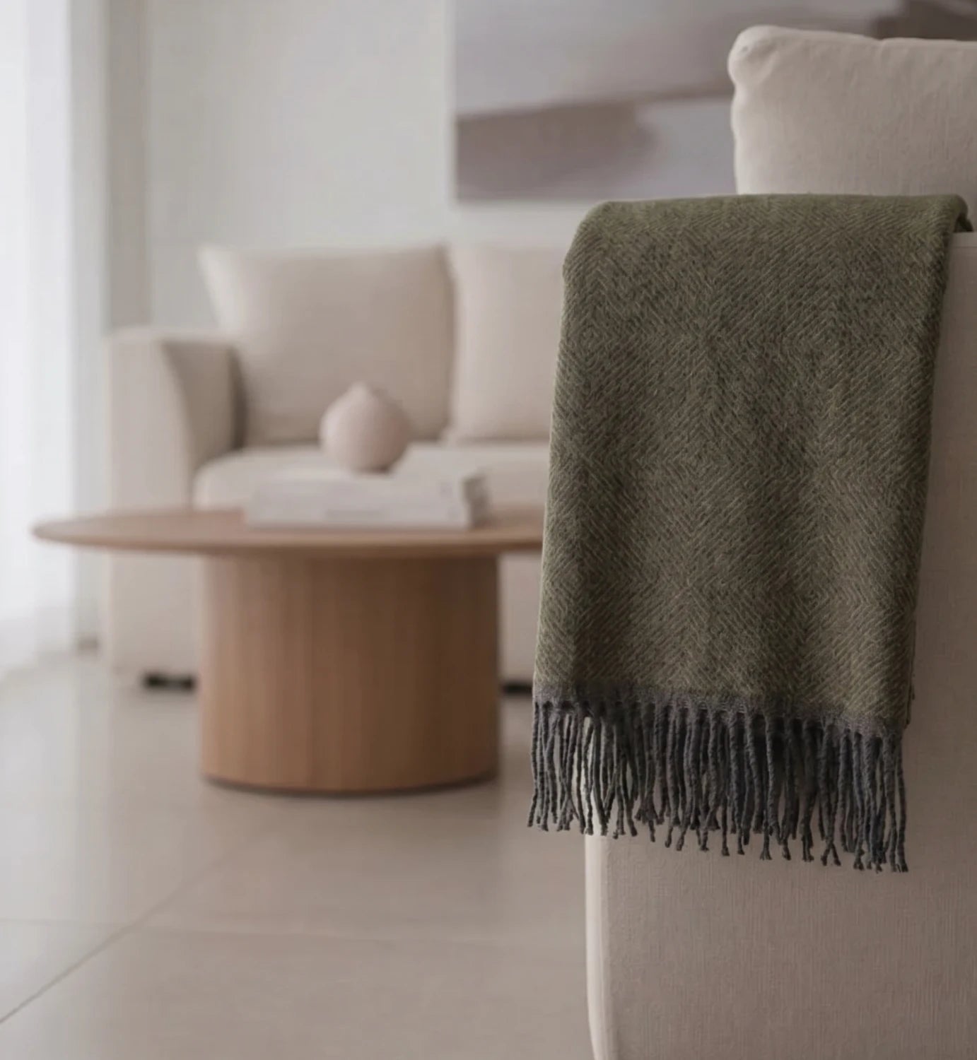 Green throw blanket draped over a chair in a modern living room.