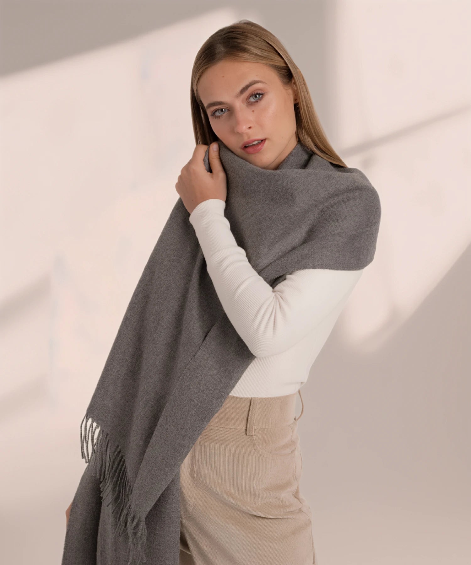 Woman wearing a gray scarf with a plain background