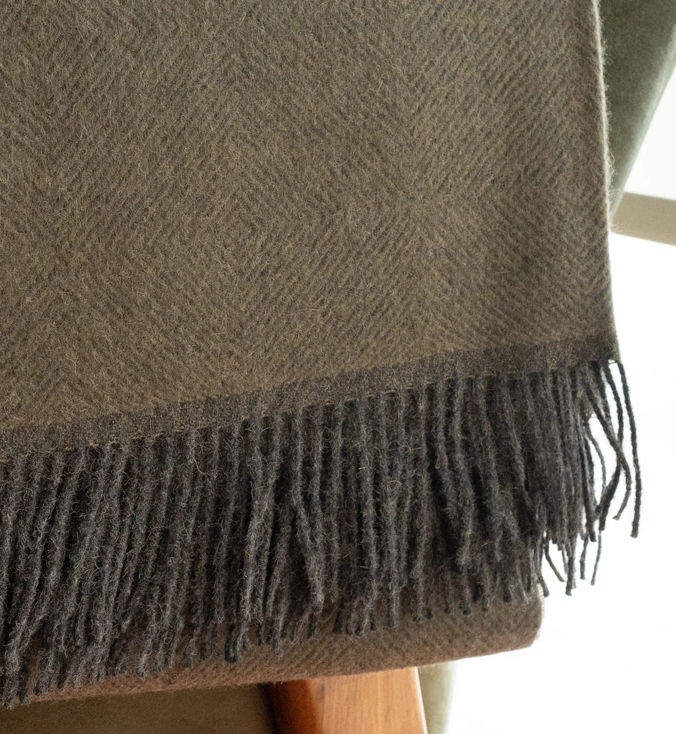 Close-up of a brown woven blanket with fringes on a blurred background