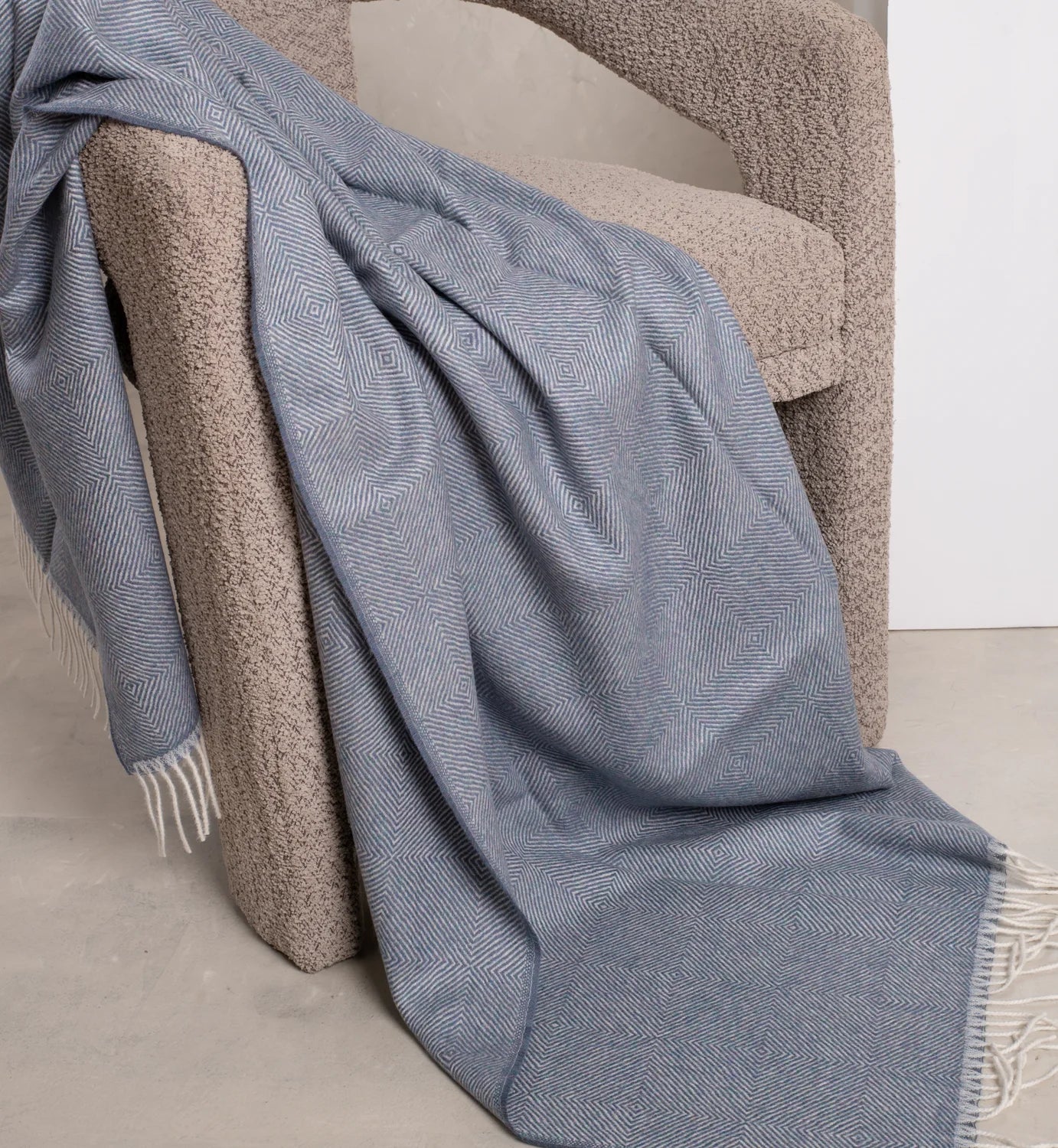Blue patterned throw blanket draped over a textured chair.