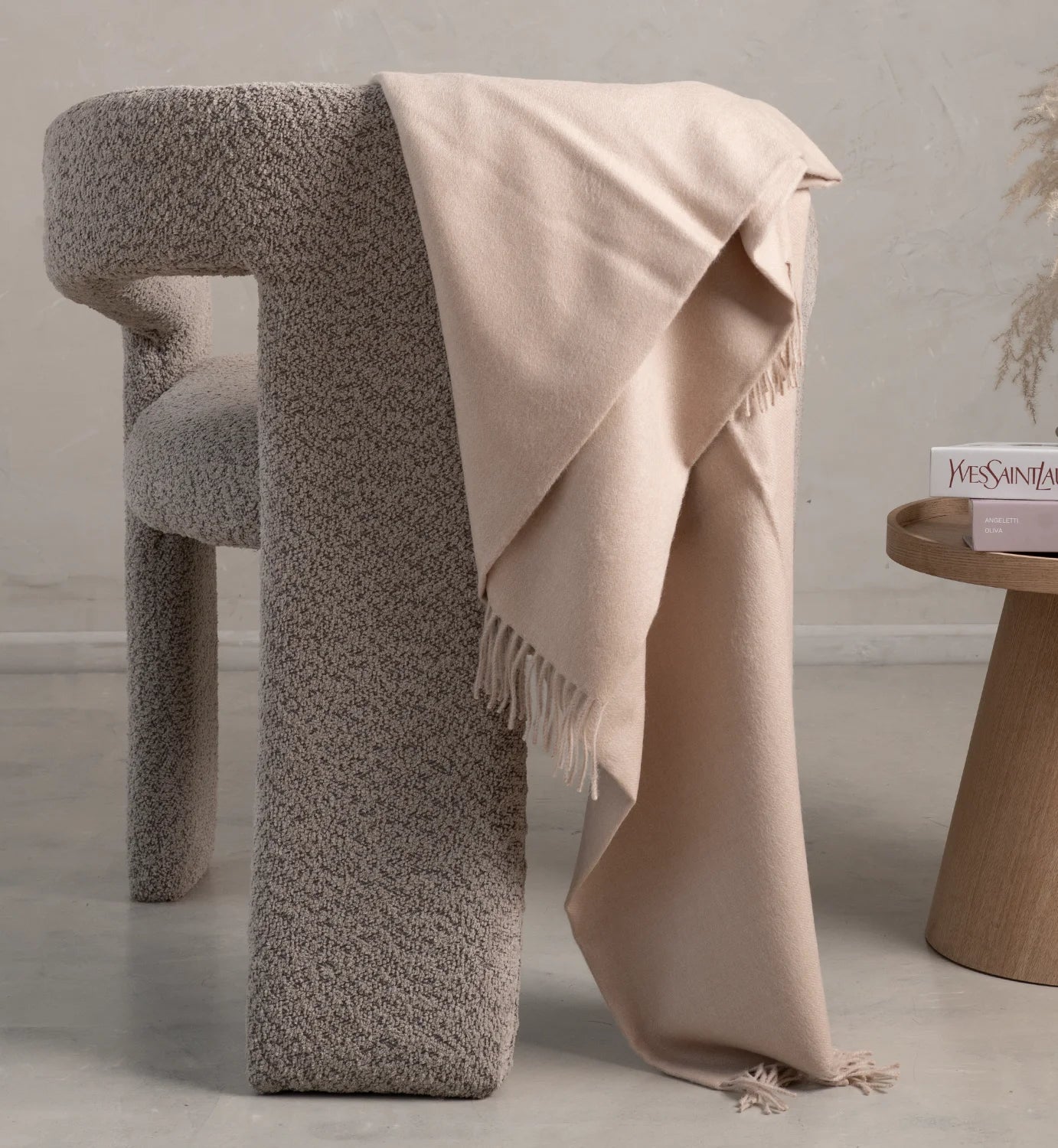 Textured stool with a beige blanket draped over it in a minimalistic setting.