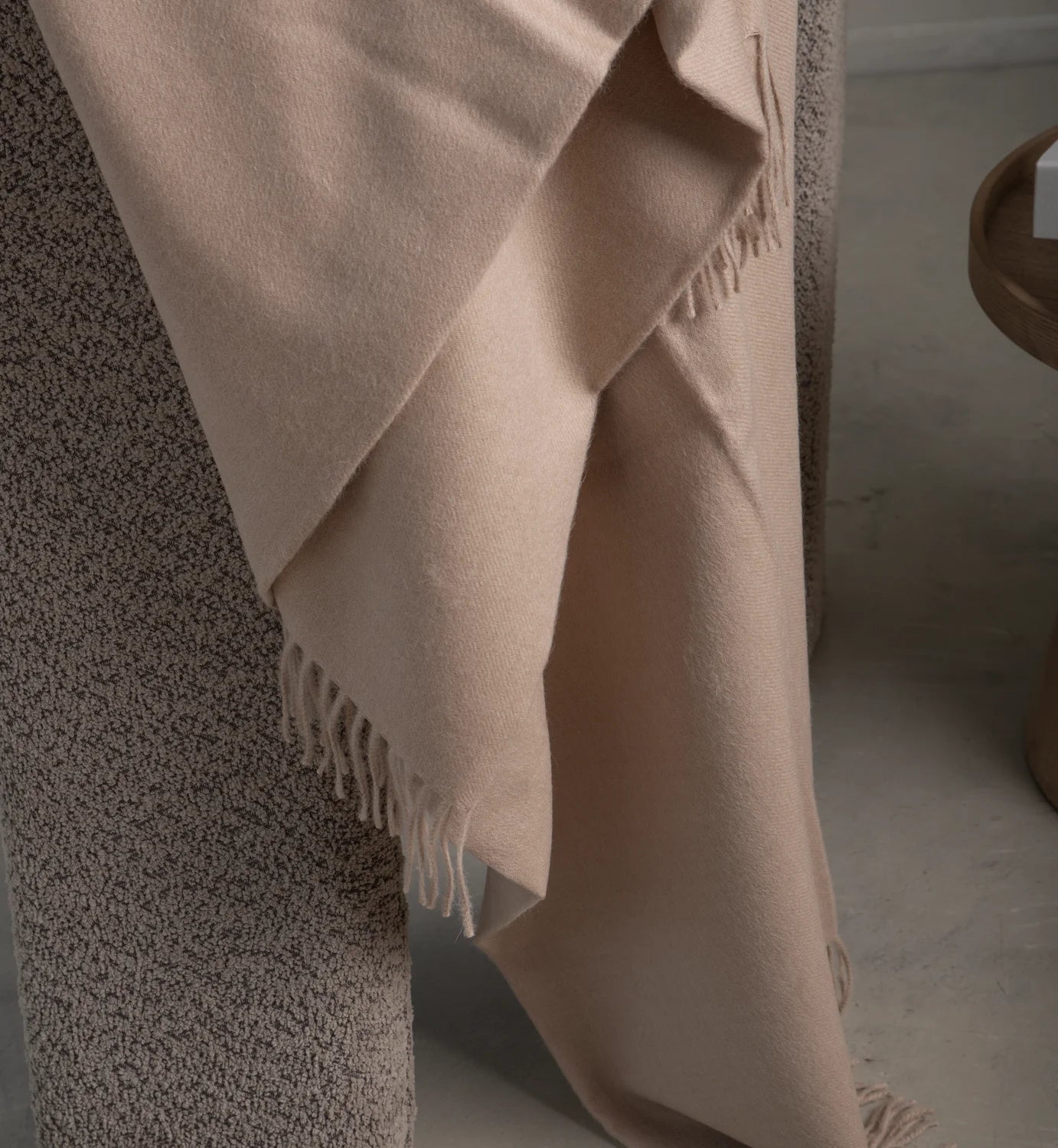 Beige shawl draped over a person wearing patterned pants on a neutral background