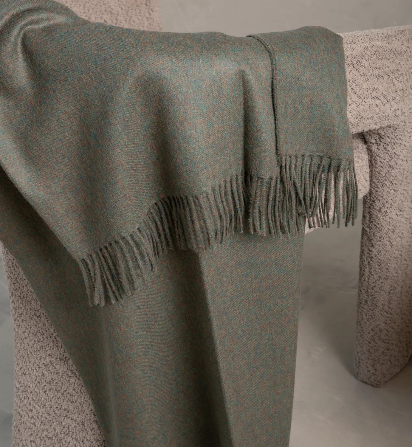 Baby Alpaca Green plaid blanket with fringe draped over a textured surface