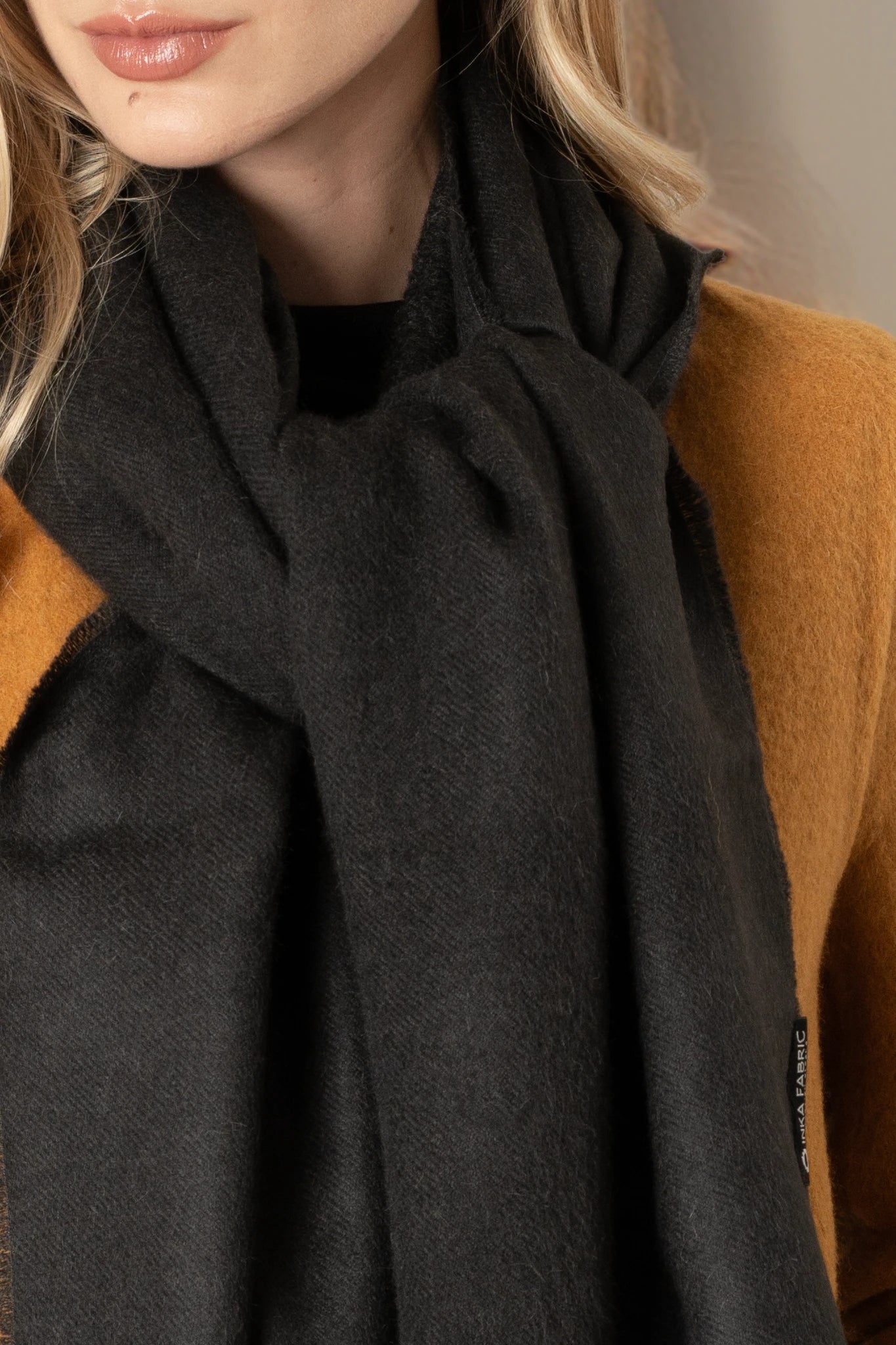 Person wearing a dark gray scarf over a brown garment