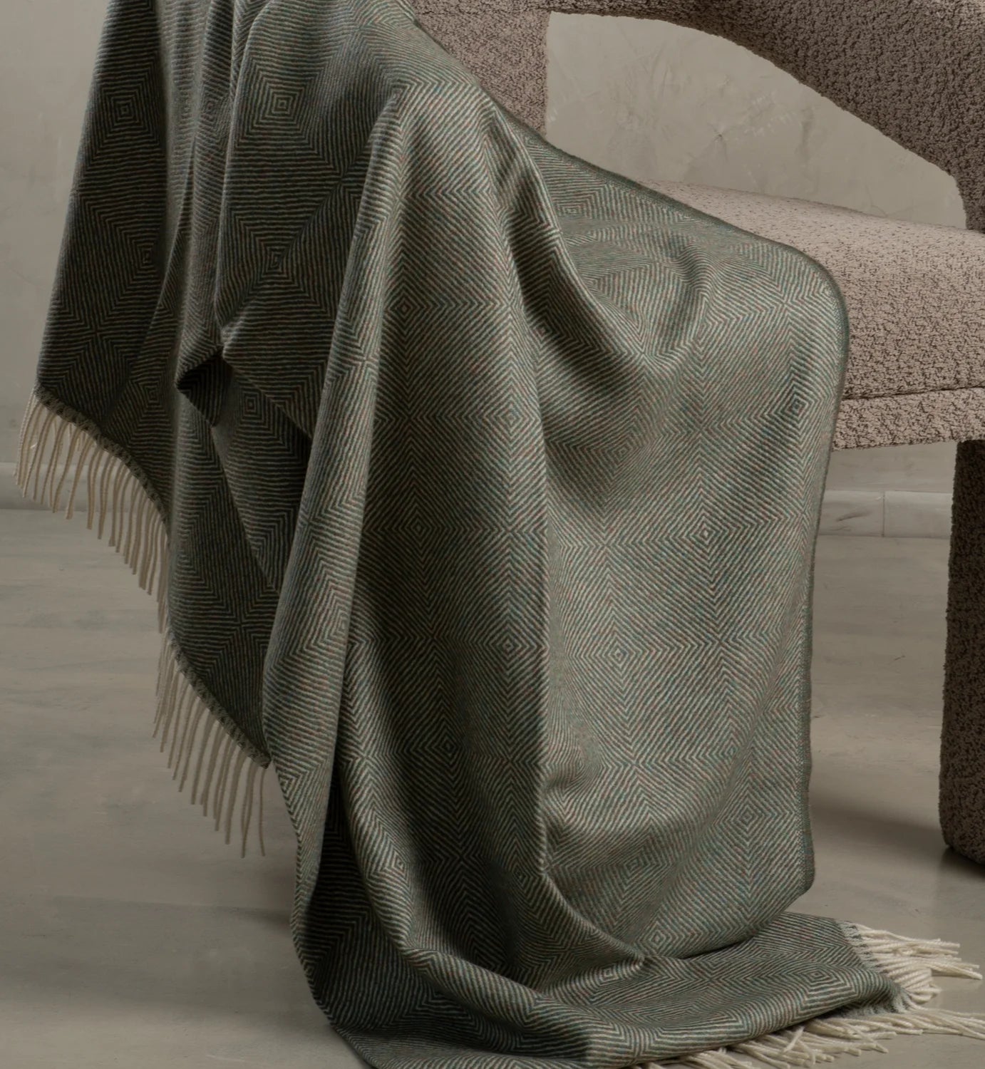 Green textured throw blanket with fringe on a chair made with alpaca fiber