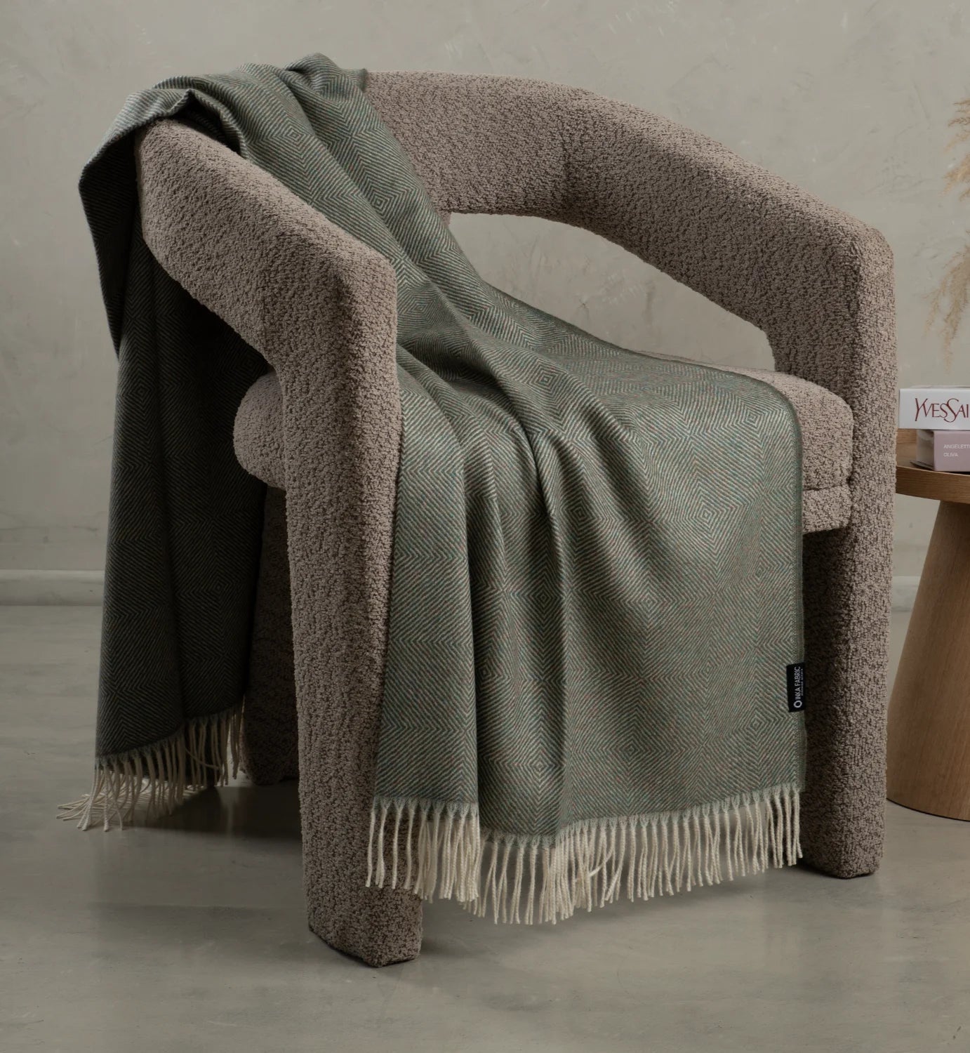 alpaca Green blanket draped over a brown armchair with a neutral background