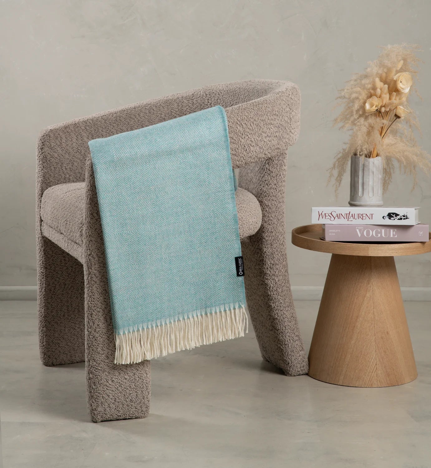 Chair with an alpaca blue blanket draped over it, next to a wooden side table with decor items.