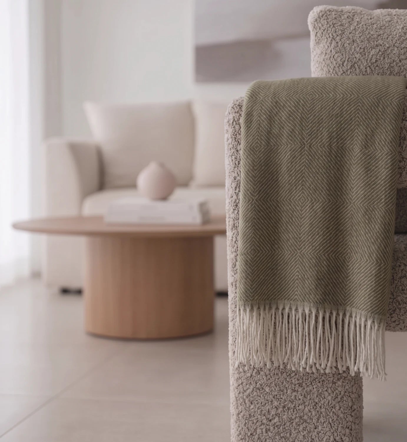 Green blanket draped over a textured chair in a modern living room.