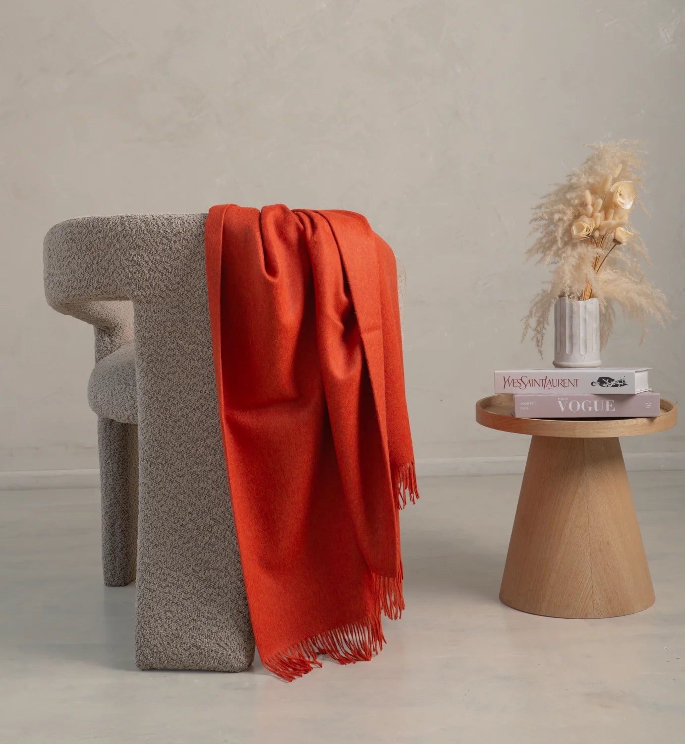 alpaca Red blanket draped over a textured gray stool with a small wooden table holding decor items.
