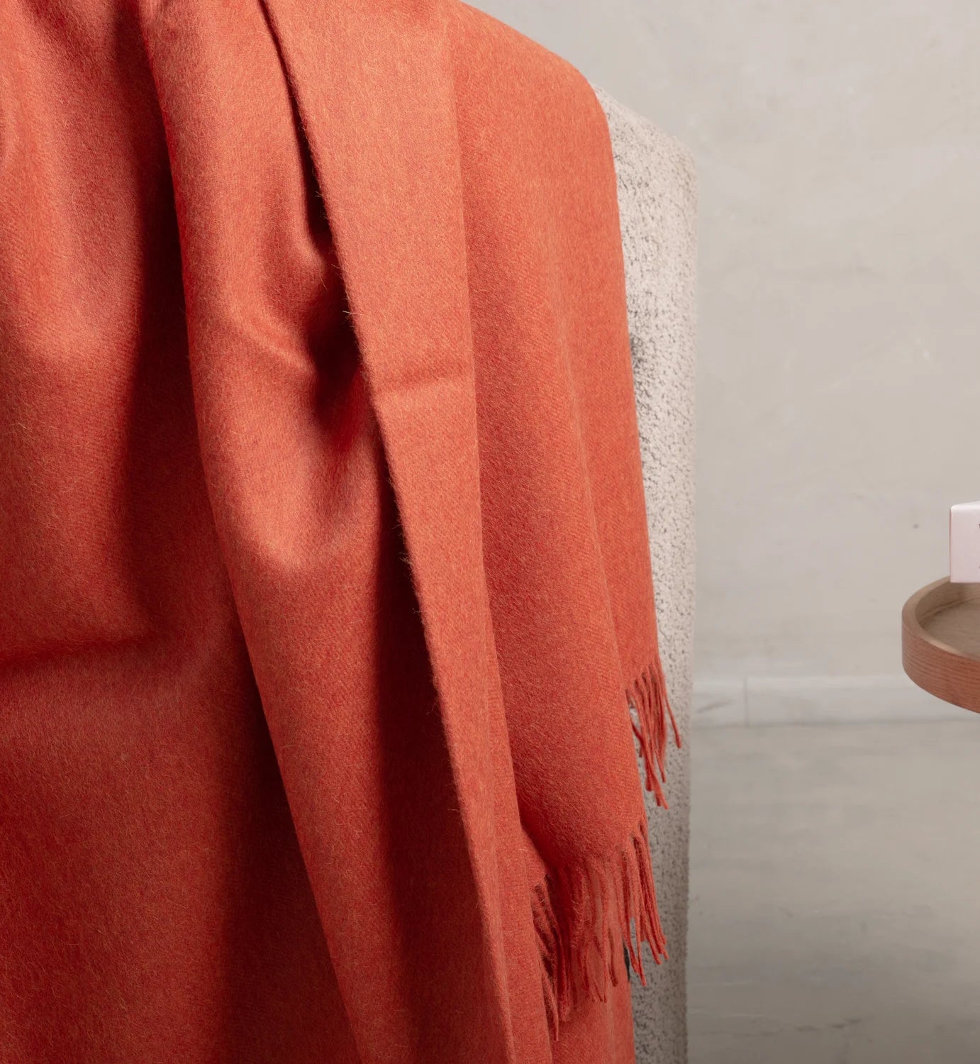 alpaca Orange throw blanket draped over a chair with a neutral background