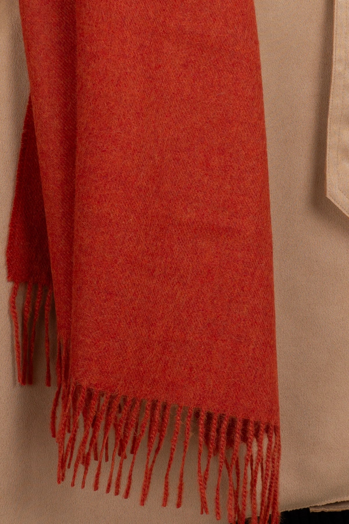 Red scarf with fringes draped over a beige surface