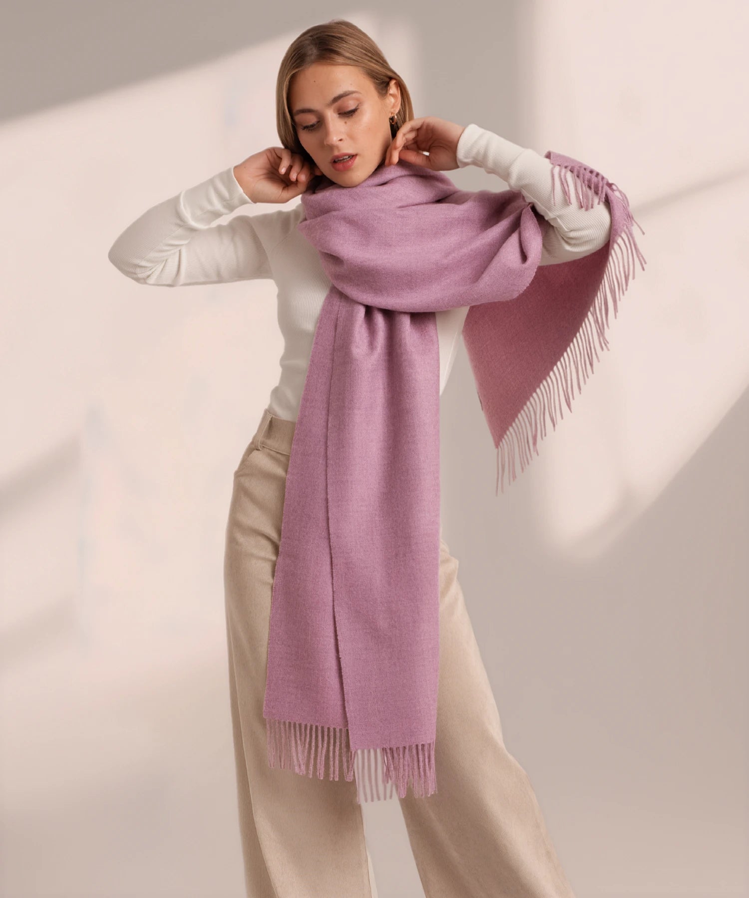 Woman wearing a pink scarf against a plain background