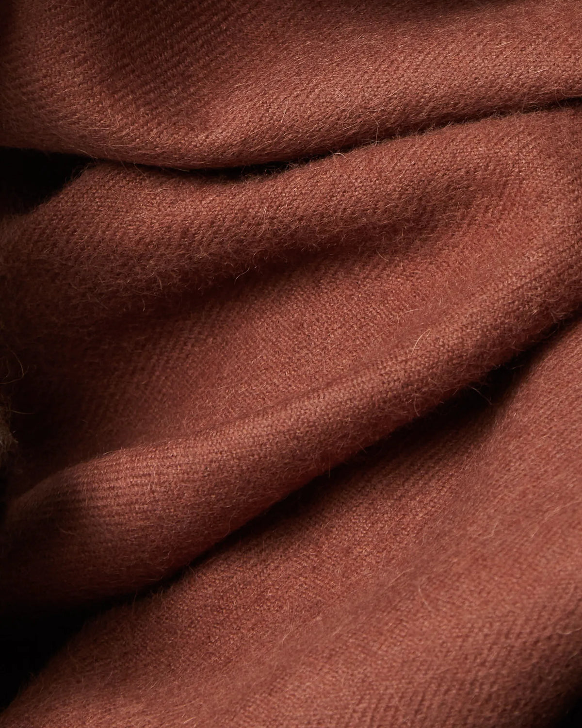 A close-up of draped dusty rose or mauve-colored fabric with a soft, slightly fuzzy texture.