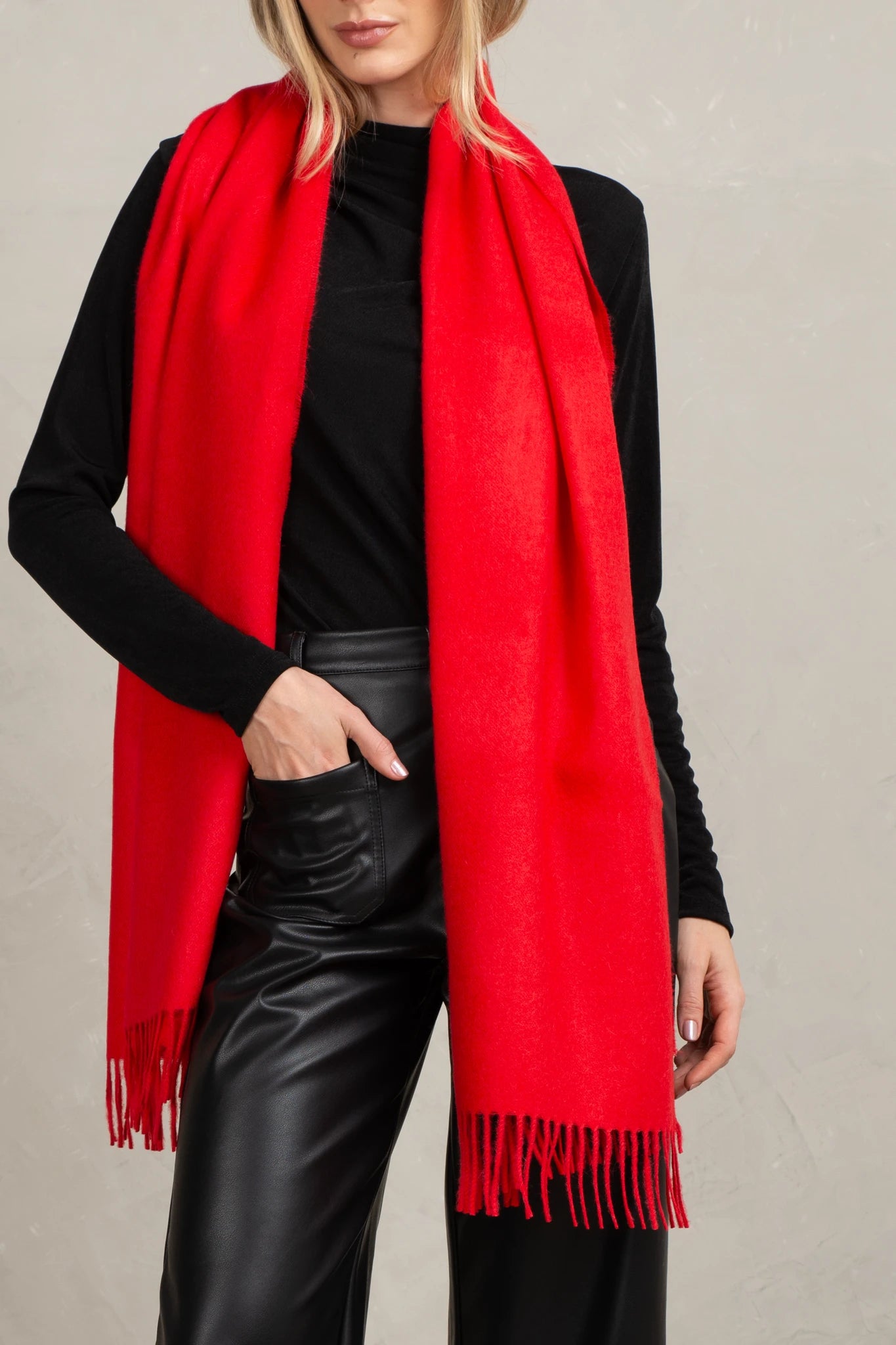 Person wearing a red scarf over a black outfit on a neutral background