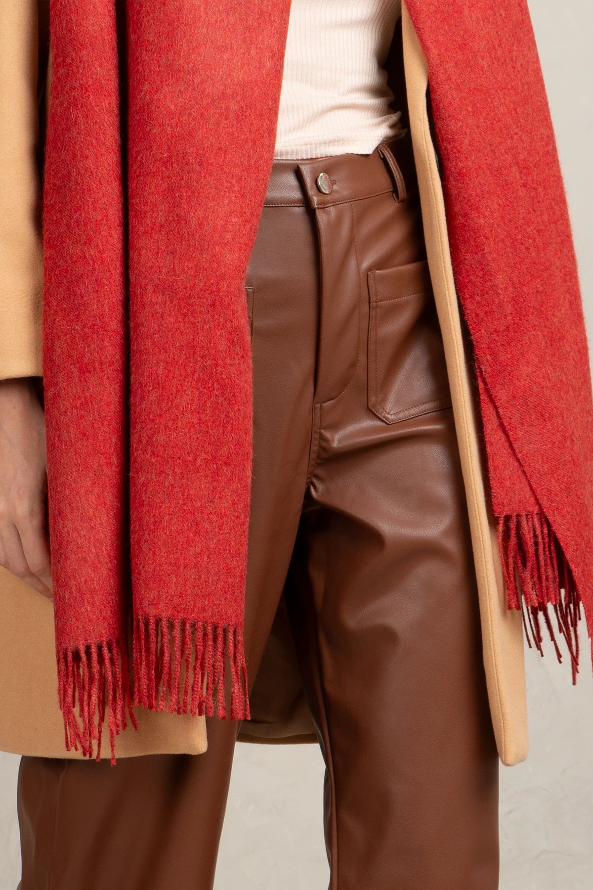 Person wearing a 100% baby alpaca red scarf, beige coat, and brown pants on a neutral background