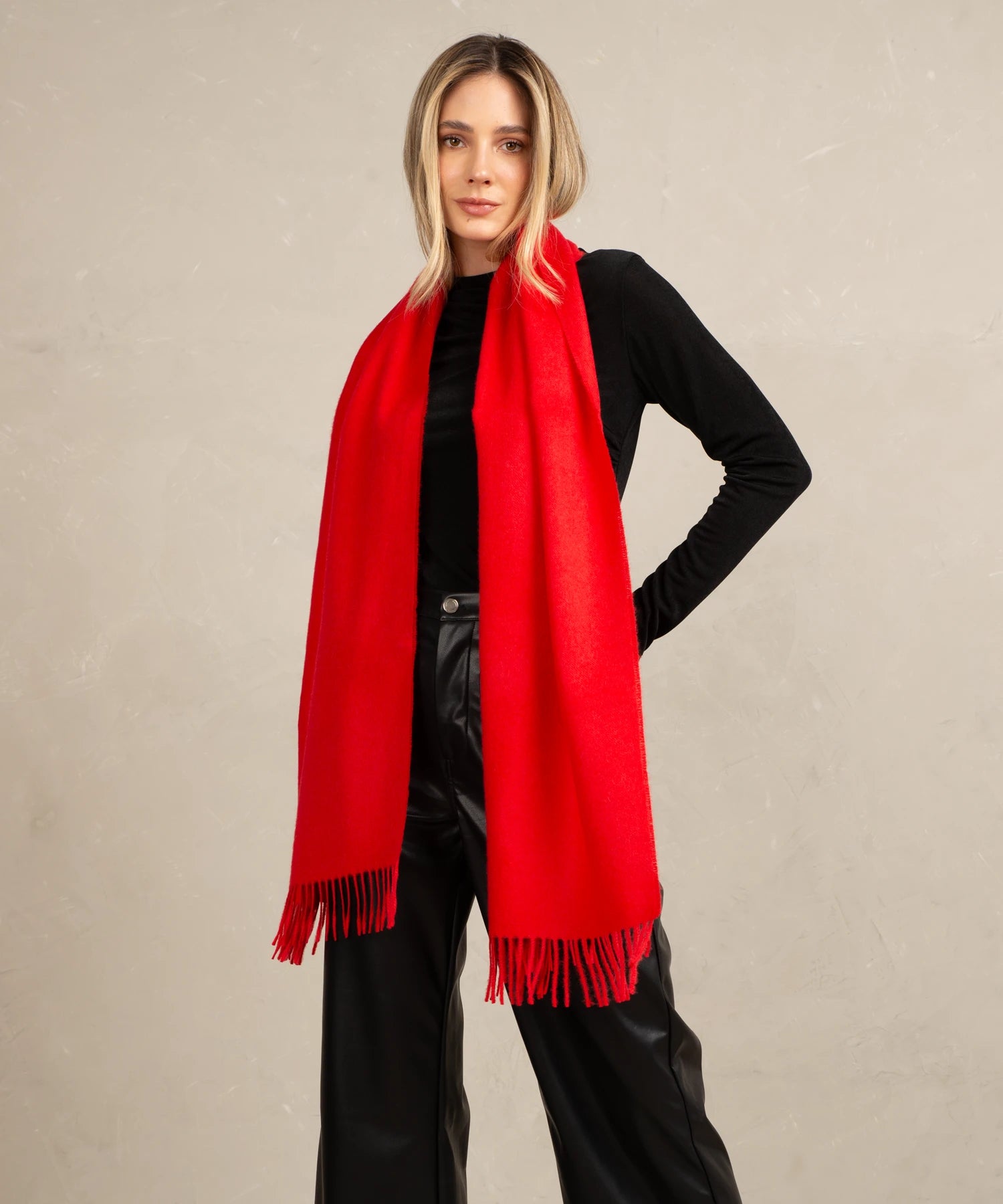 Woman wearing a red scarf and black outfit on a beige background