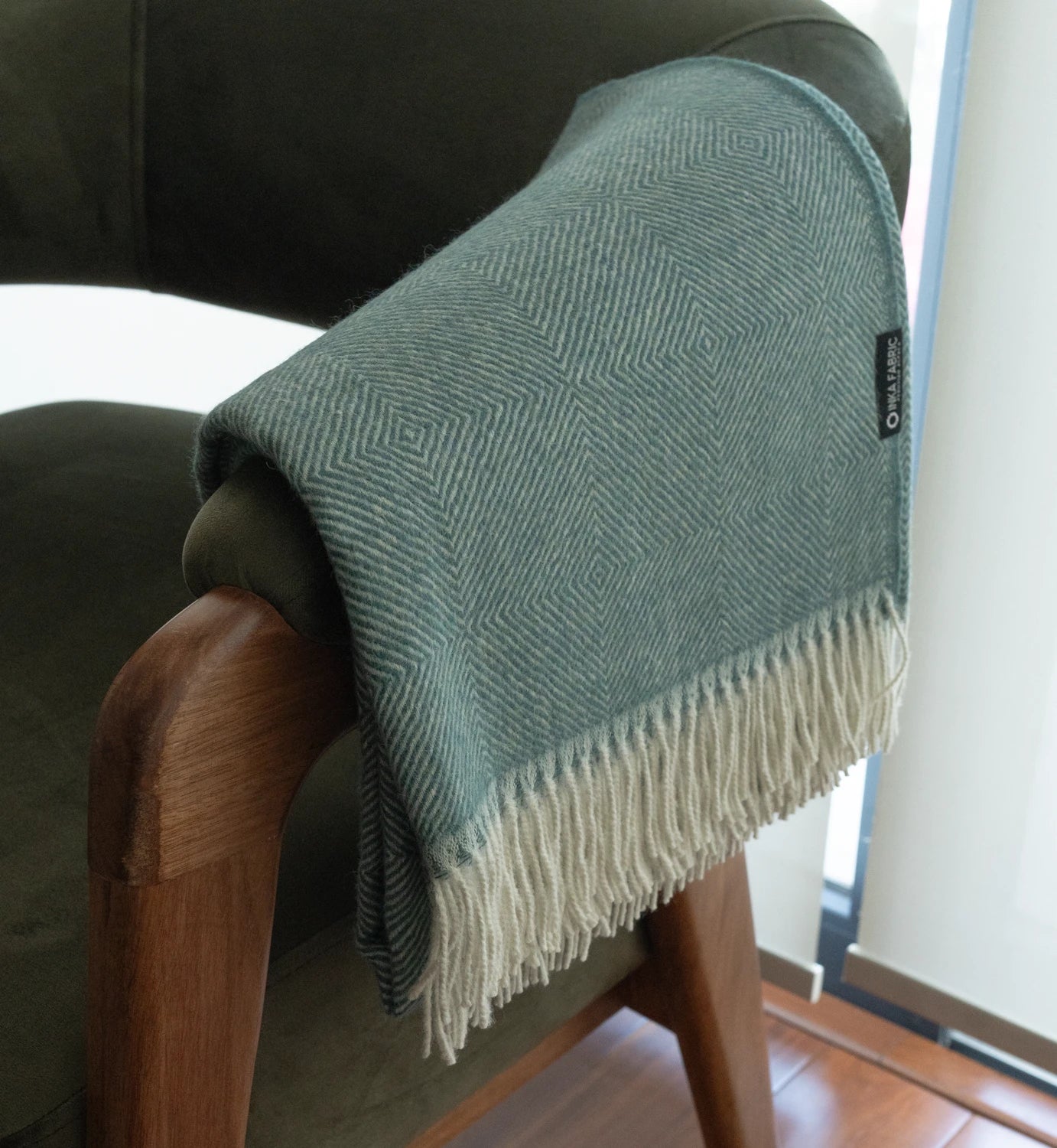 Green textured blanket draped over a chair with a visible brand label.