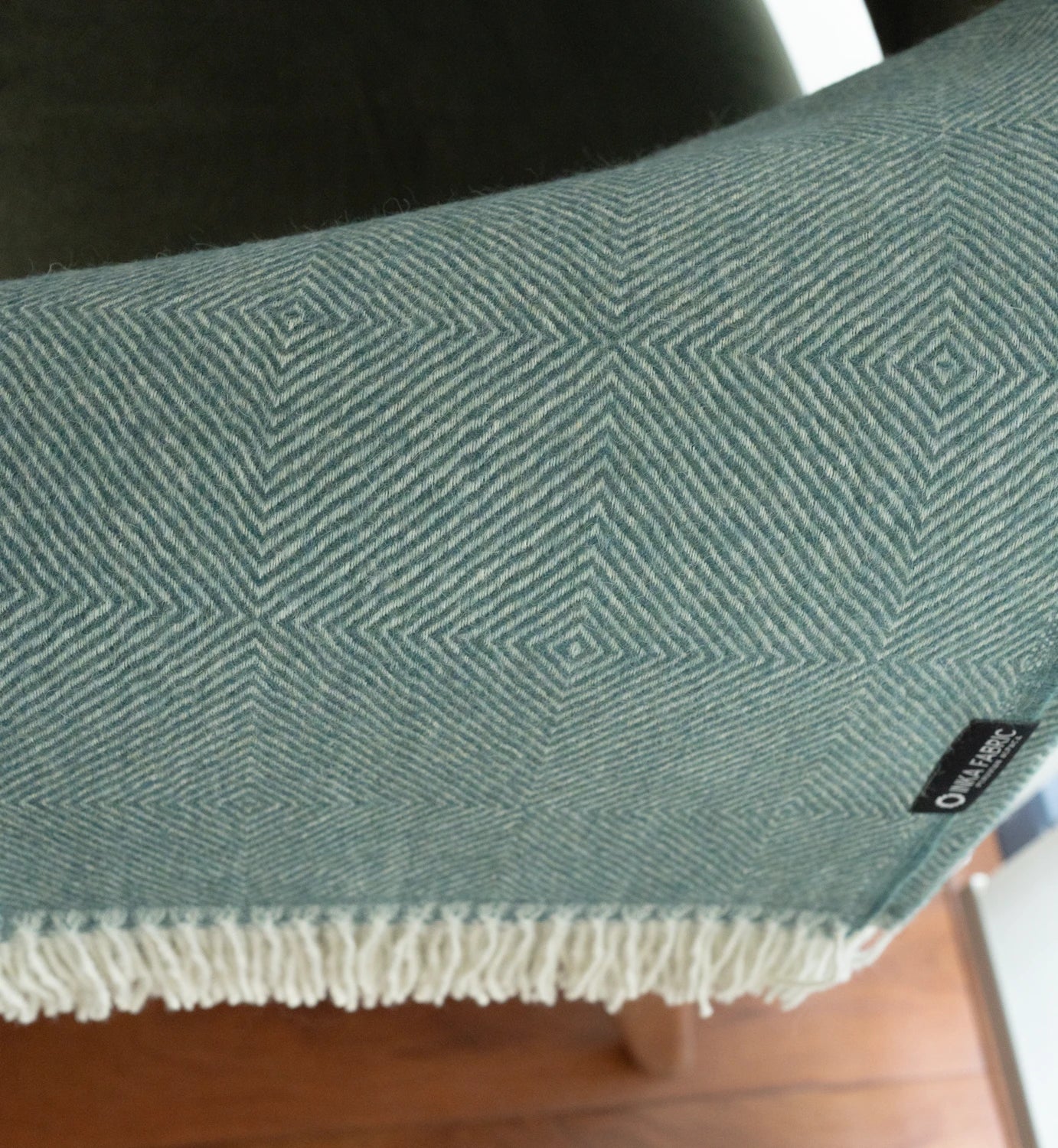 Green textured blanket with a pattern on a wooden surface
