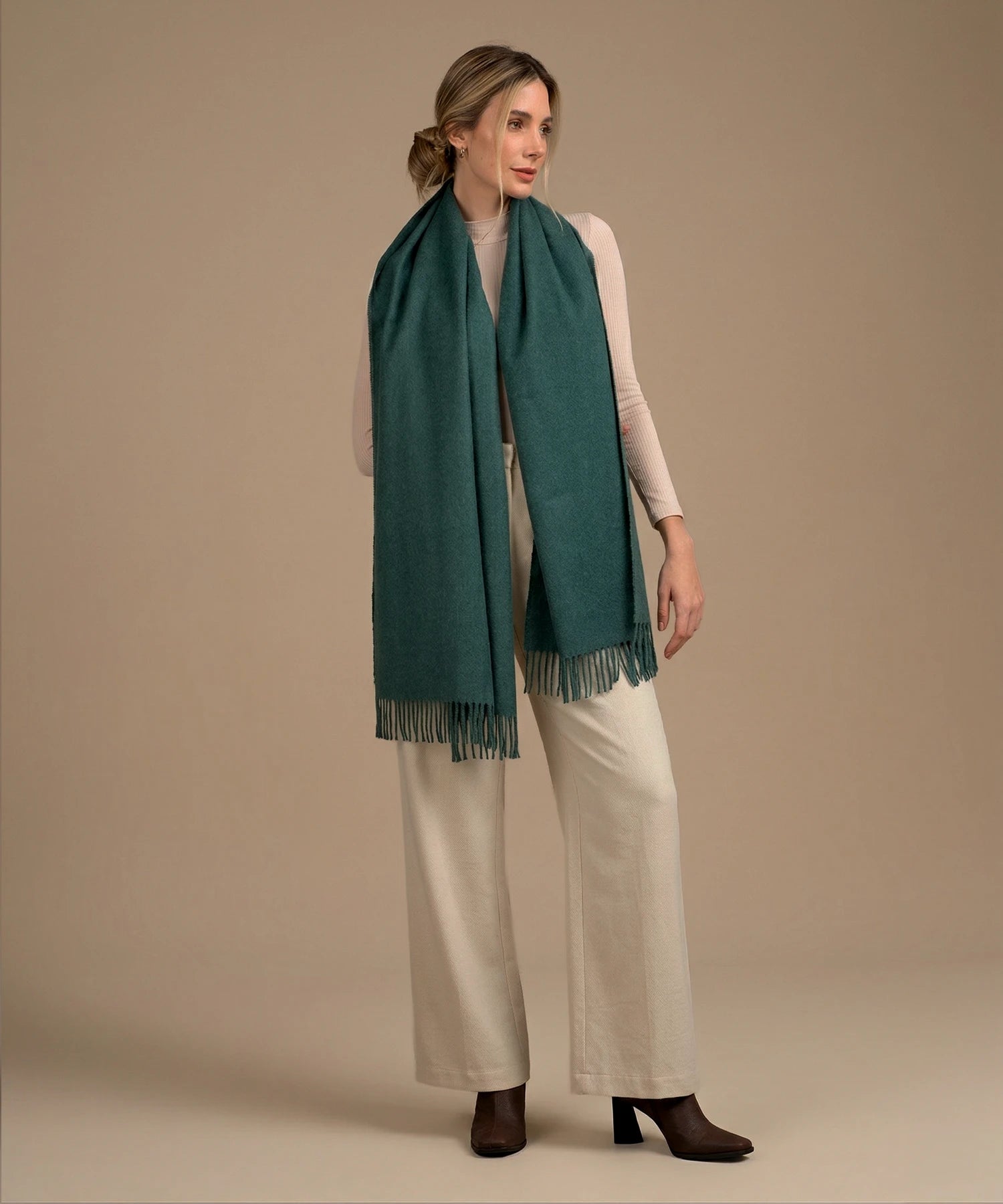 Woman wearing a teal scarf with a plain background