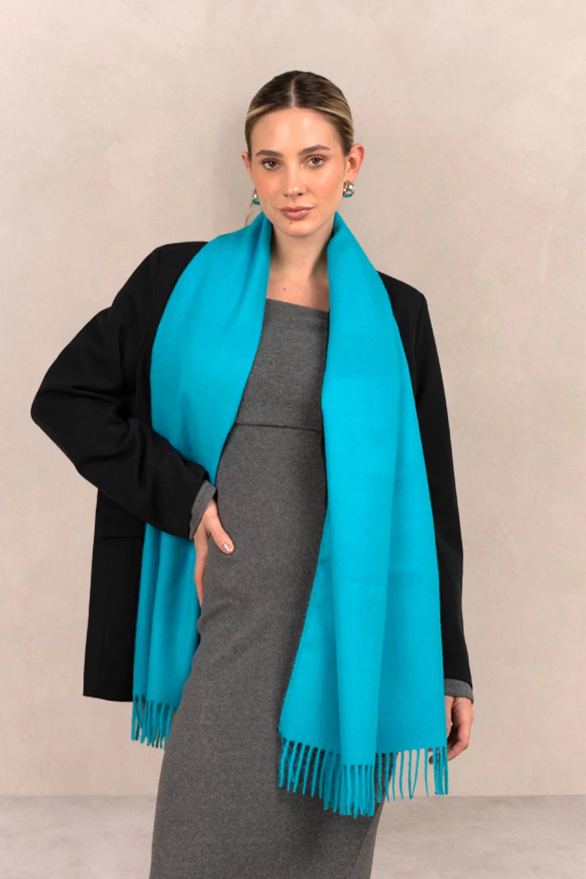 Woman wearing a turquoise scarf with a plain background