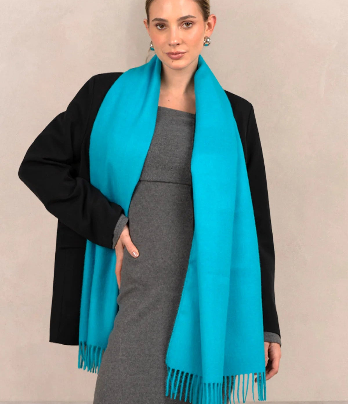 Woman wearing a turquoise scarf with a plain background