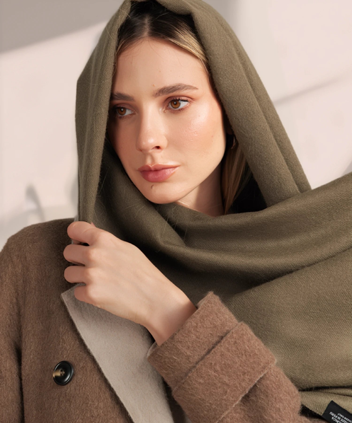 Woman wrapped in a green blanket with a neutral background