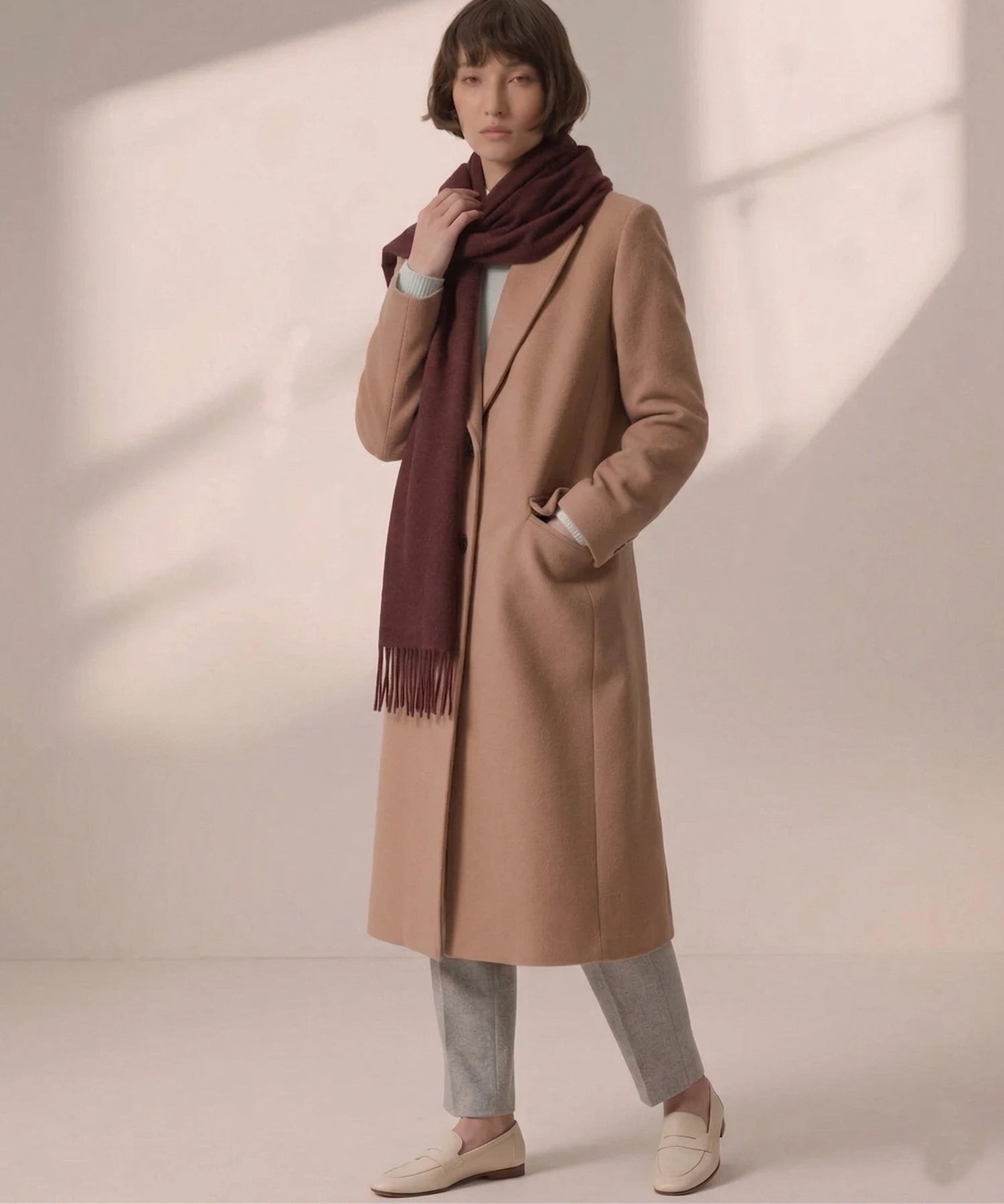 una mujer con abrigo marron con una bufanda color vino