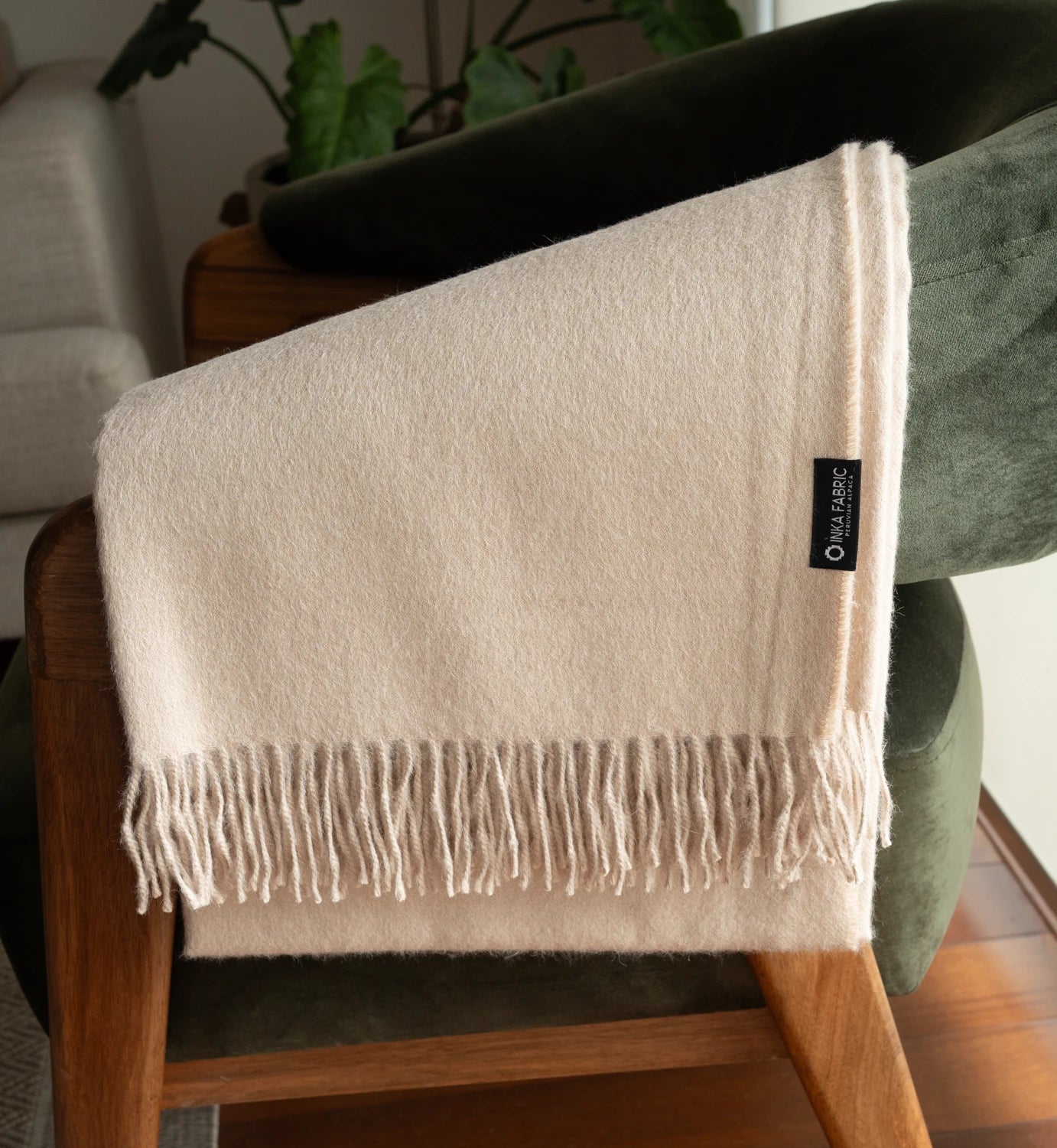 Beige throw blanket with tassels on a wooden chair in a home setting