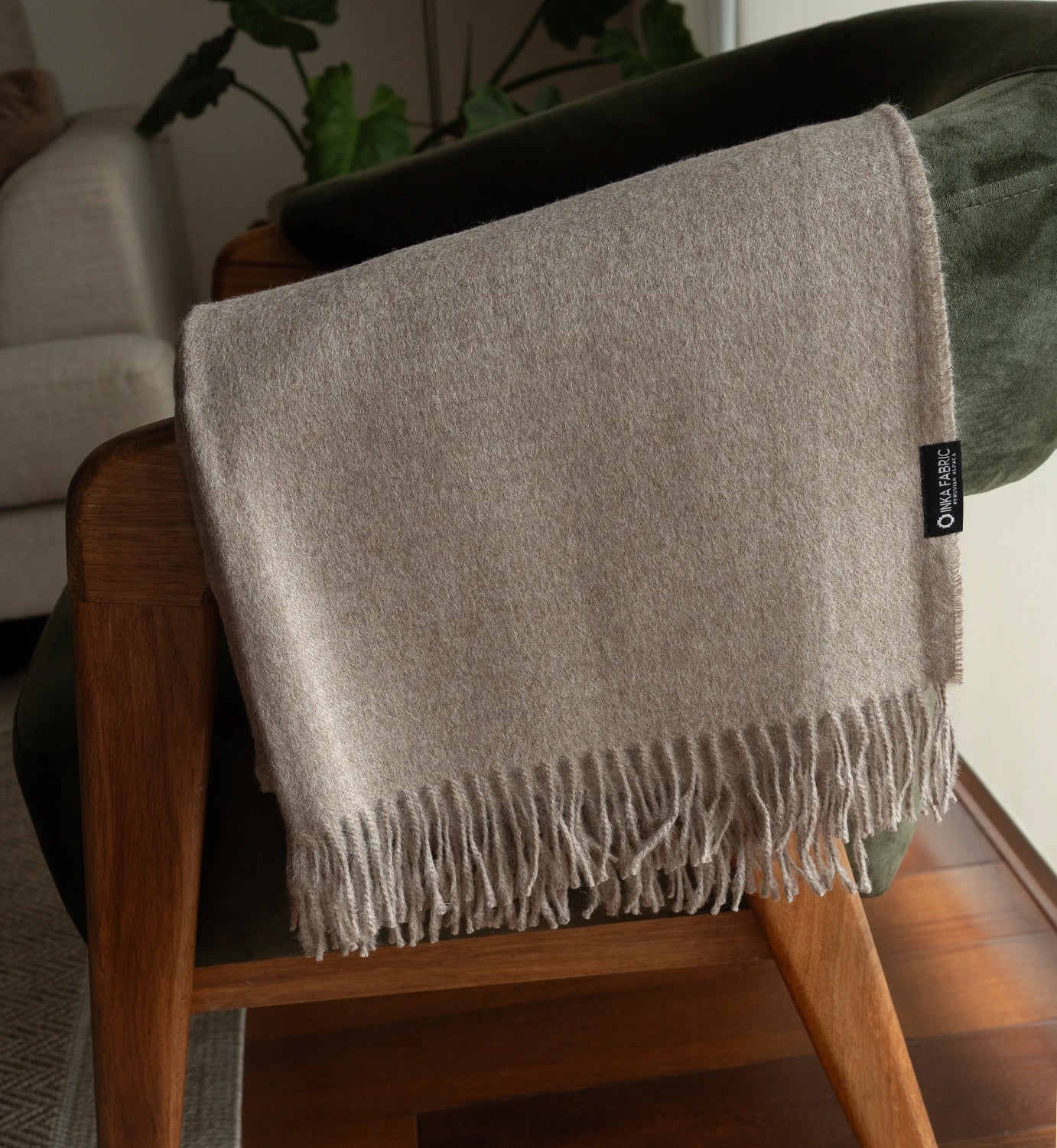 Beige throw blanket with tassels on a wooden chair in a home setting
