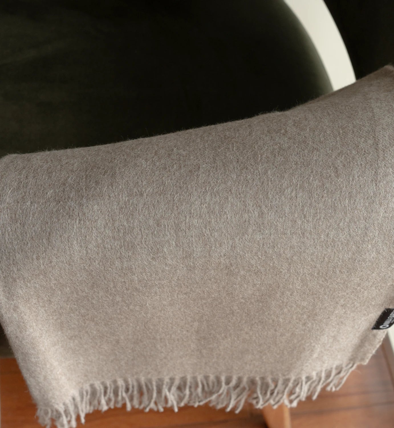 Gray woven blanket with fringes on a wooden surface