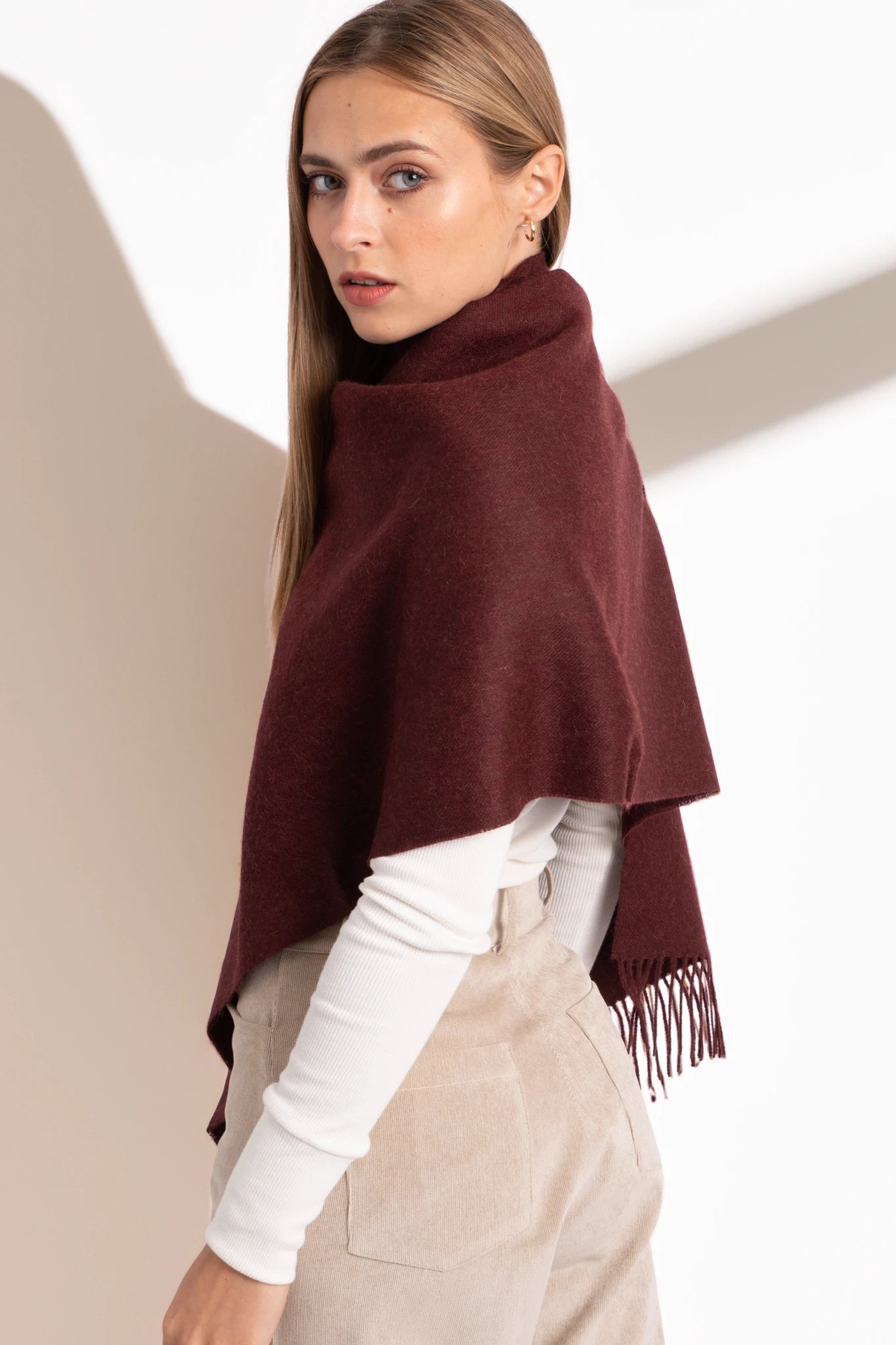 Woman wearing a burgundy poncho with a plain background