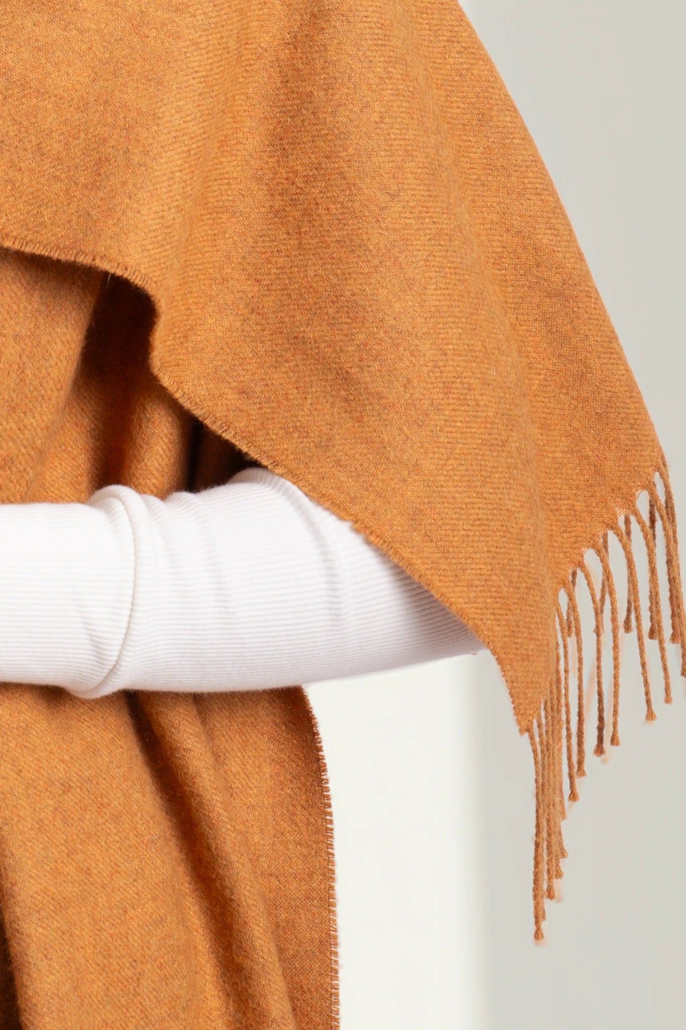 Brown poncho with fringe draped over a white surface