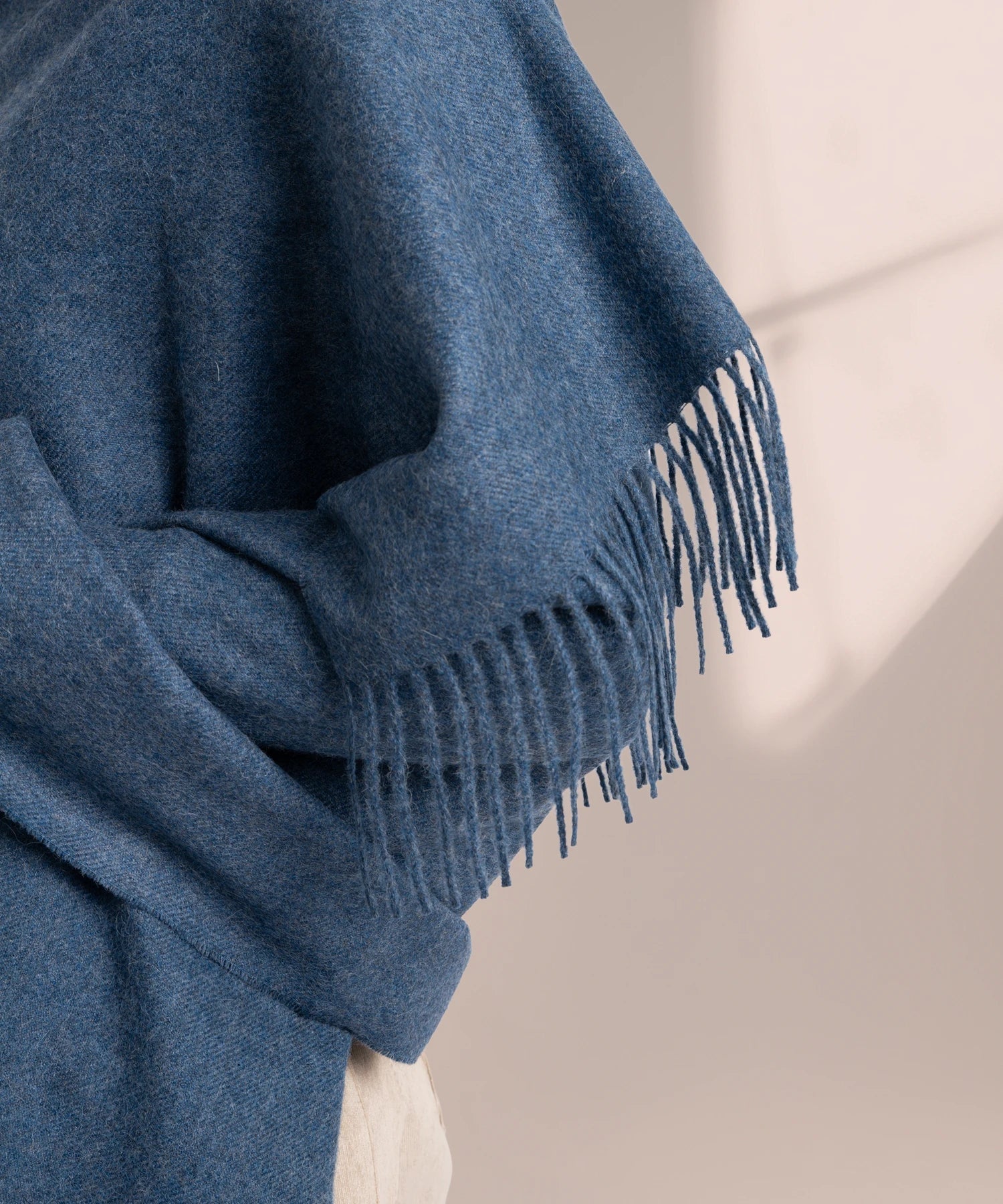 Blue scarf with fringe detail on a neutral background