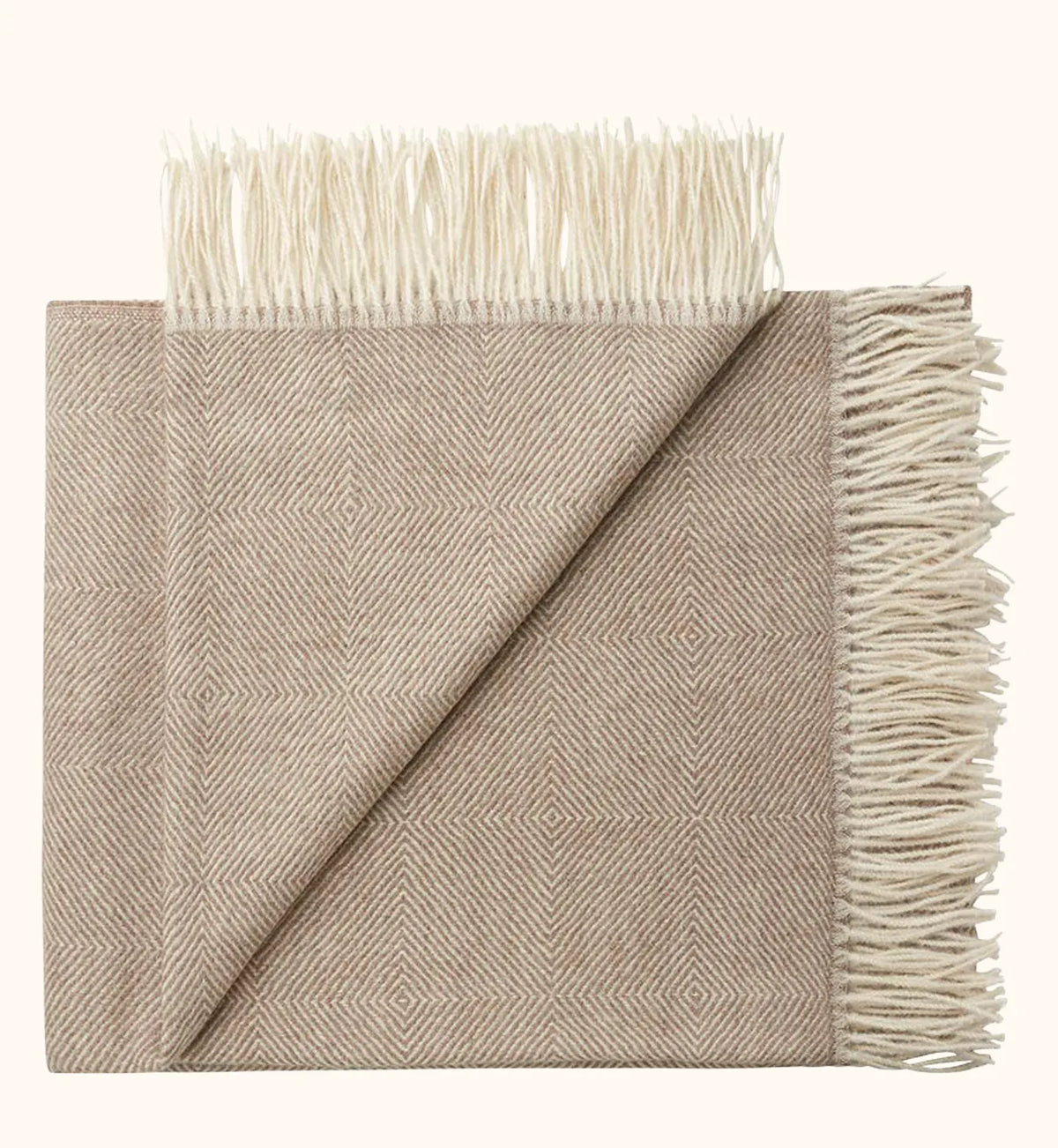 A folded woven throw blanket with fringe, shown on a plain light beige background. The fabric has a subtle herringbone pattern in warm taupe and cream tones.