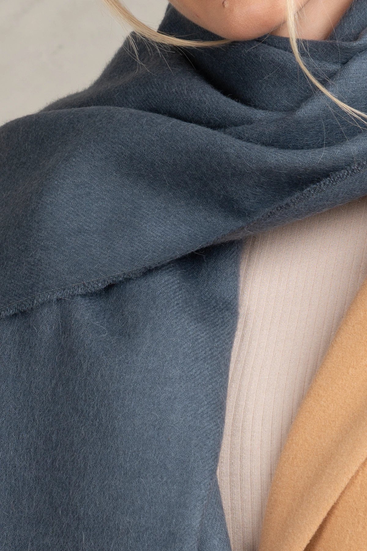 Close-up of a blue fabric draped over a person wearing a beige garment.